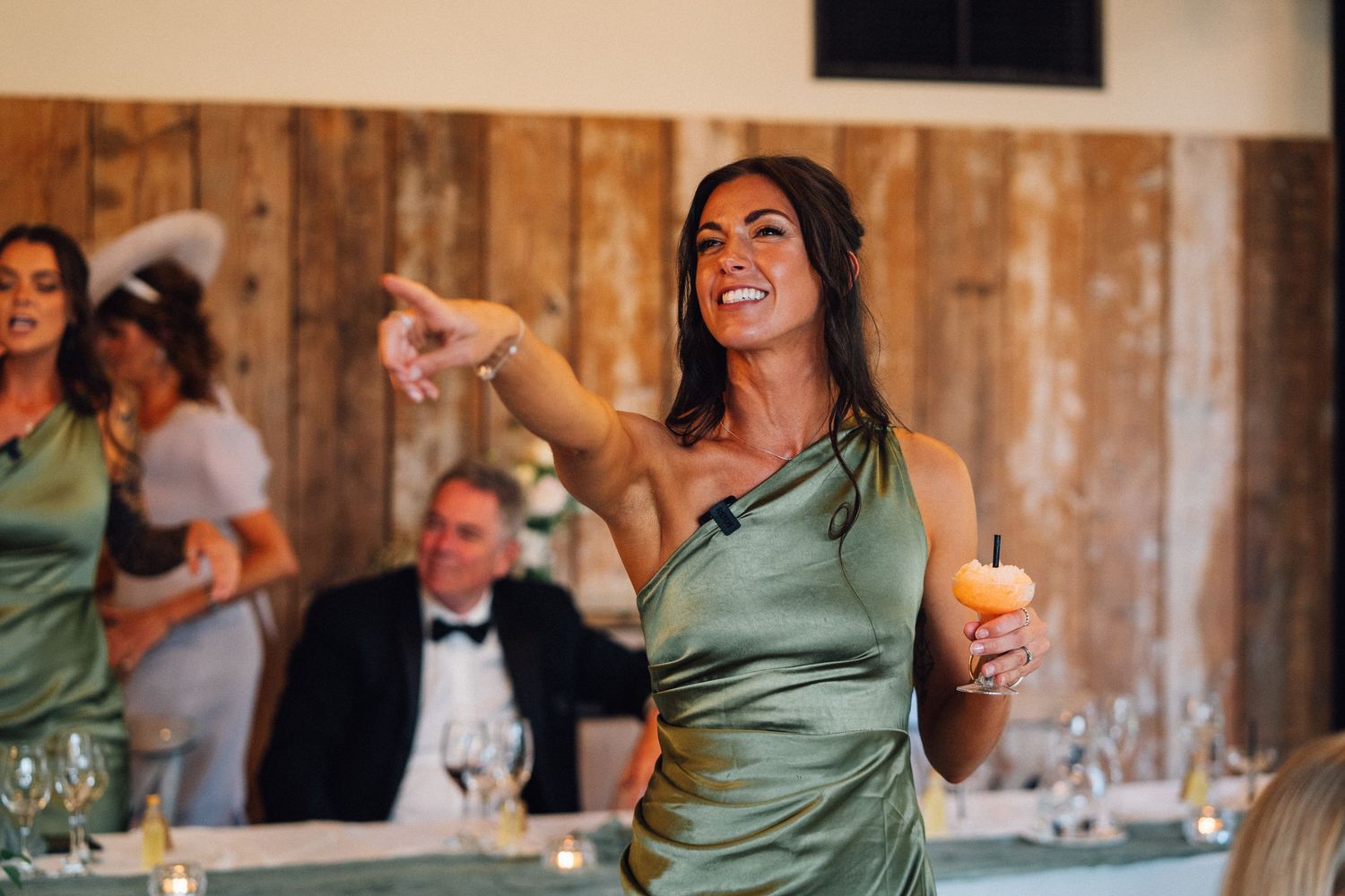 Festive wedding reception scene with guests celebrating and dancing in rustic barn setting.