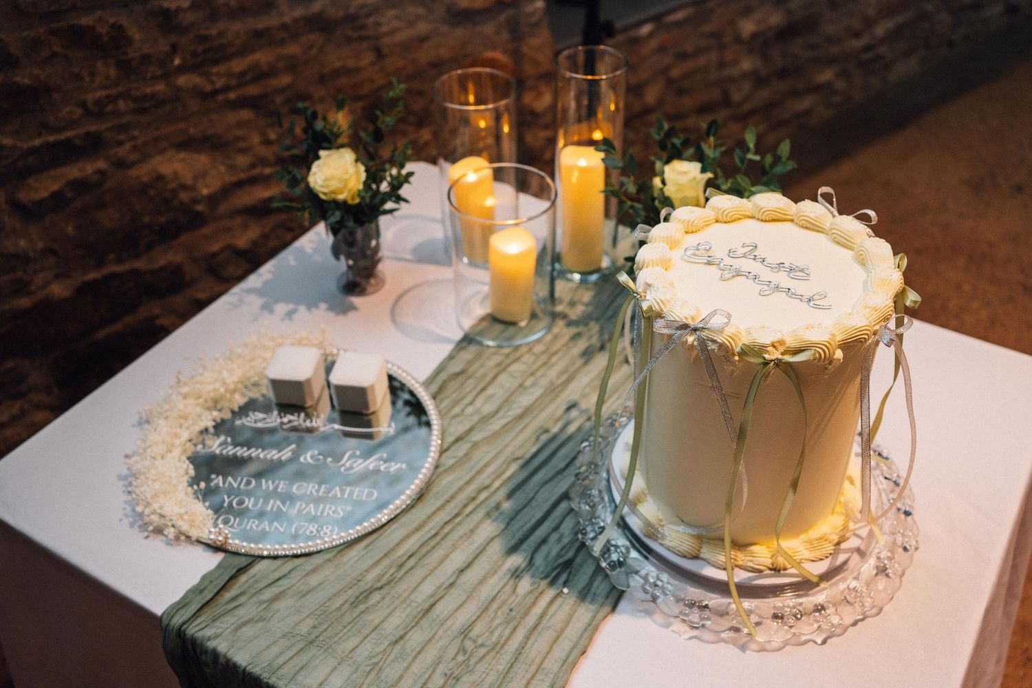 Elegant table setting with white plates, candlelight, and sage green runners for an upscale dining event.