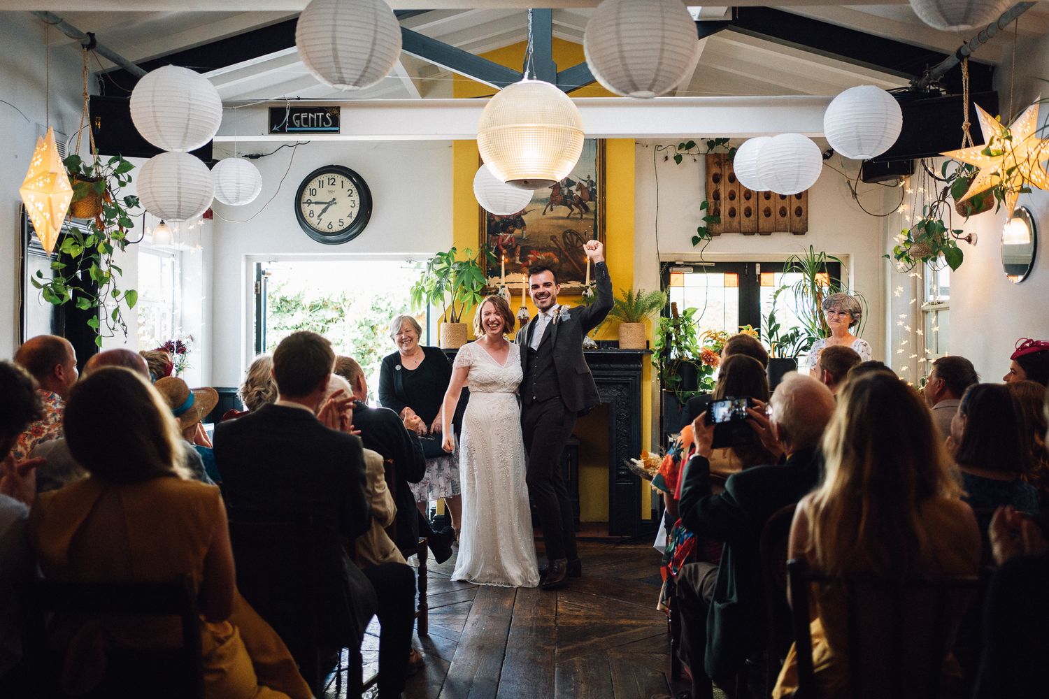 A wedding reception venue decorated with white paper lanterns and filled with guests mingling and celebrating.