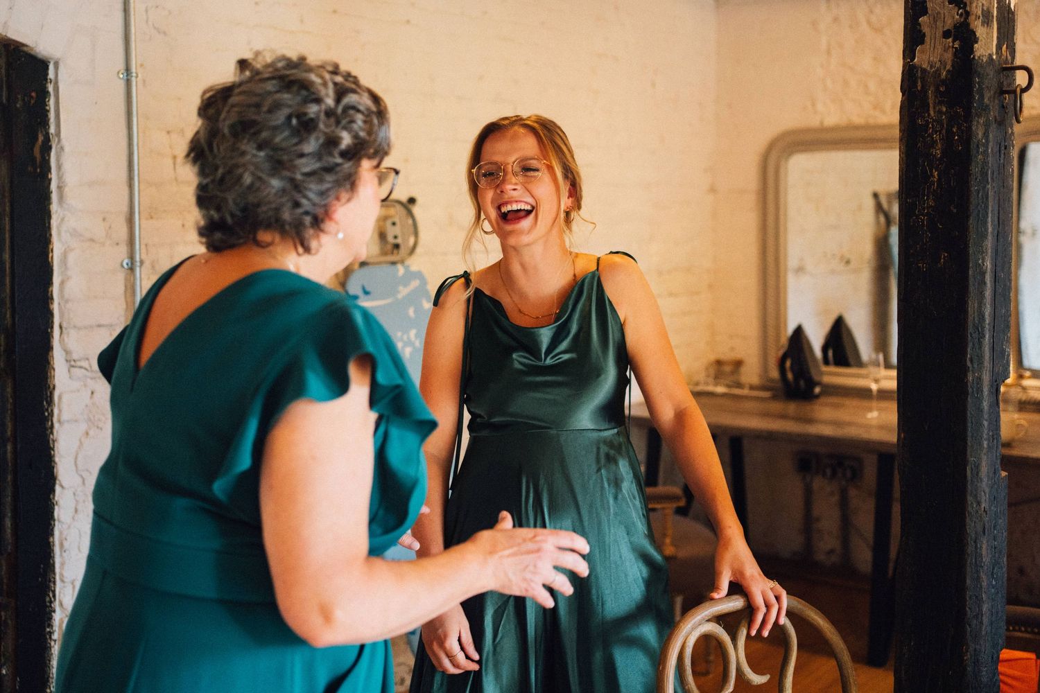 Wedding party members in teal dresses share joyful moments during pre-ceremony preparations.