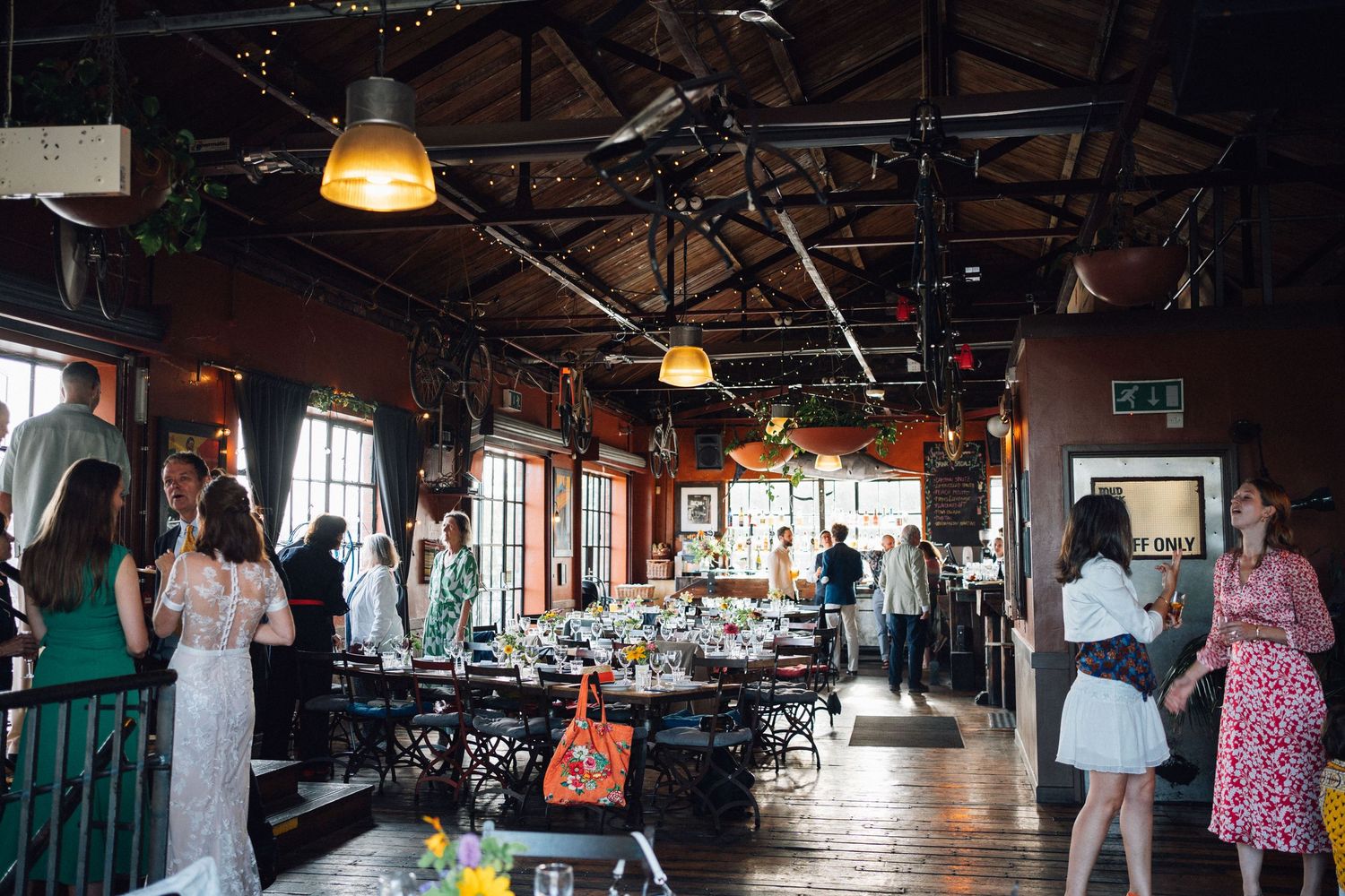 Interior view of a rustic industrial wedding venue with exposed beams and lighting.