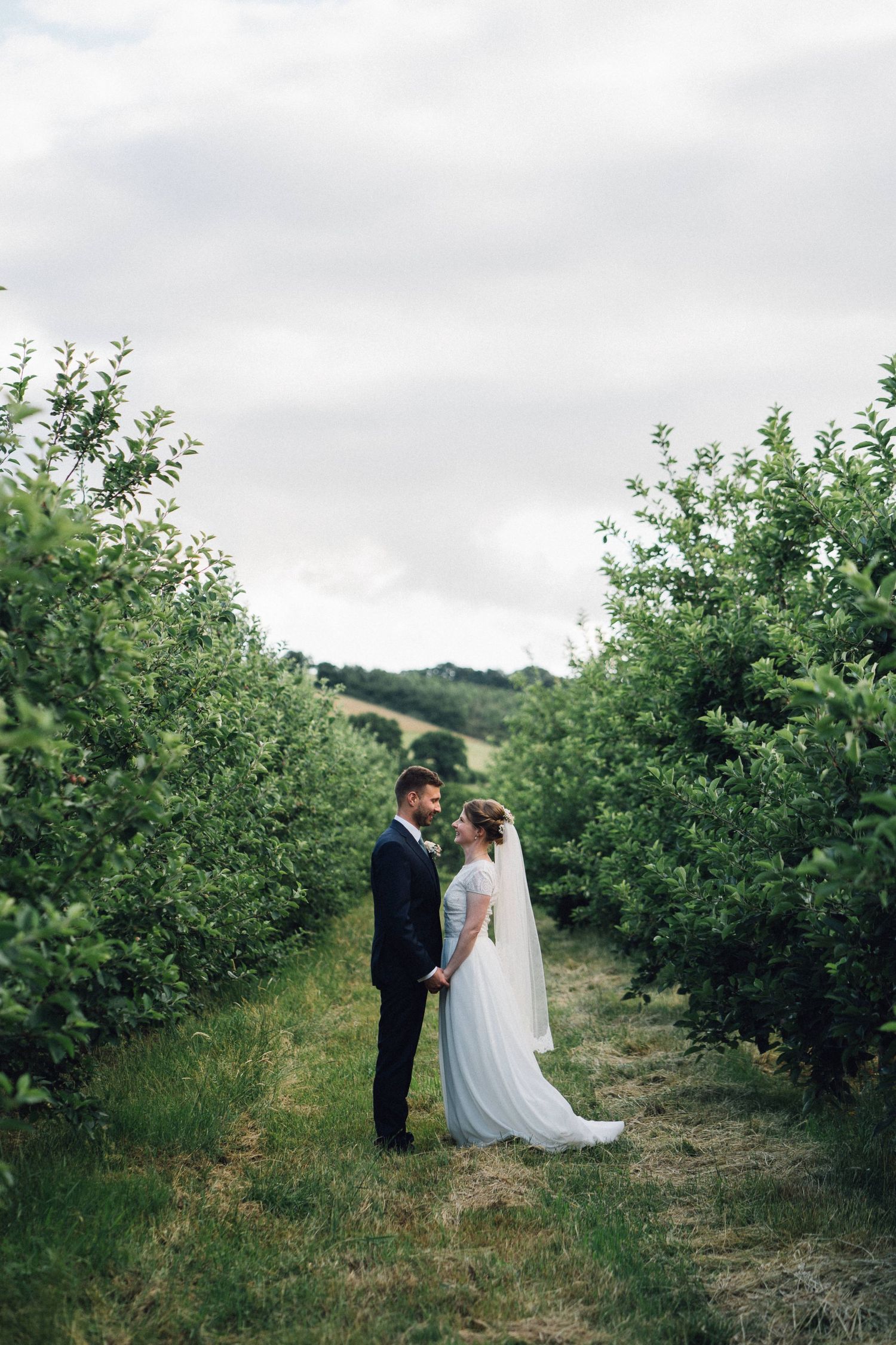 Romantic wedding portrait in an apple orchard with rolling hills in background.