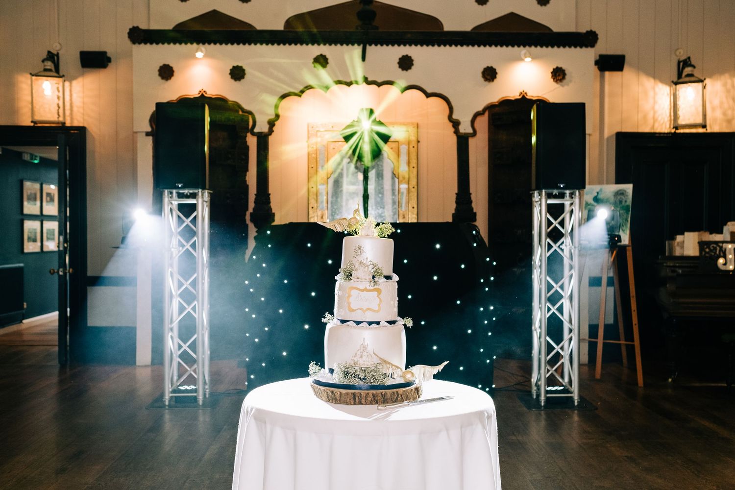 Wedding cake display with dramatic lighting and fog effects creating a magical atmosphere.