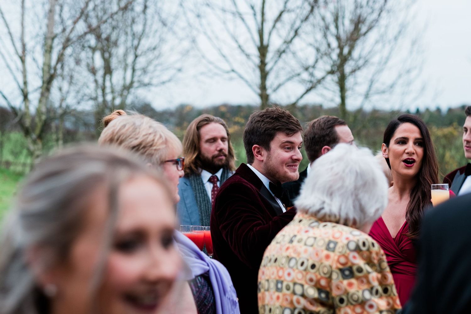Wedding guests enjoying an outdoor celebration with joyful expressions and natural scenery in the background.