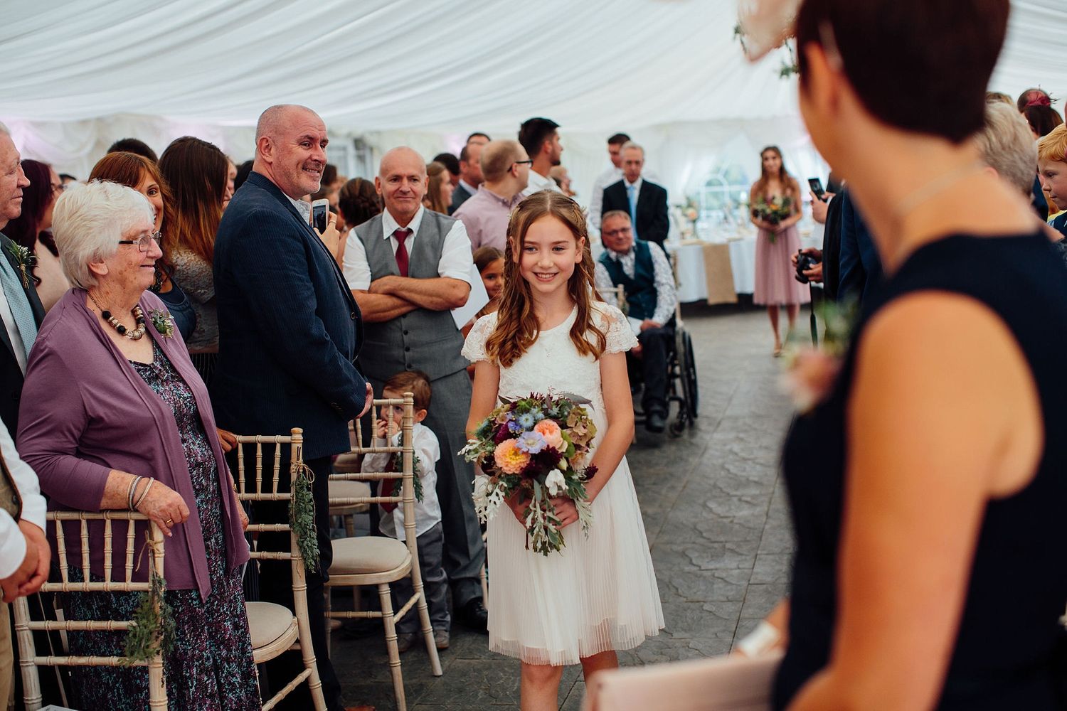 Wedding guests and bridal party gather inside an elegant white tent for the celebration.