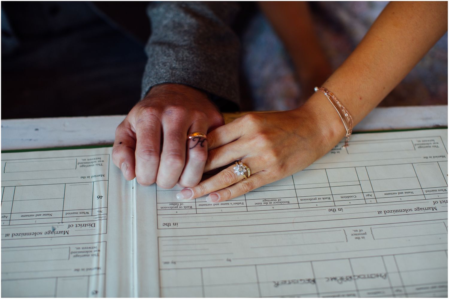 Close-up of hands signing wedding documents on official paperwork.