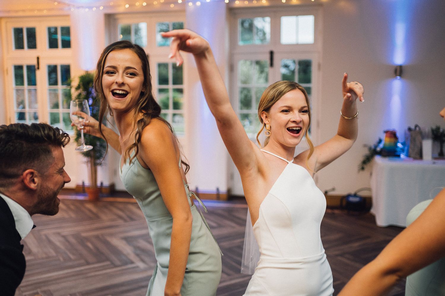 Wedding guests dancing and laughing together on a patterned dance floor at the reception.
