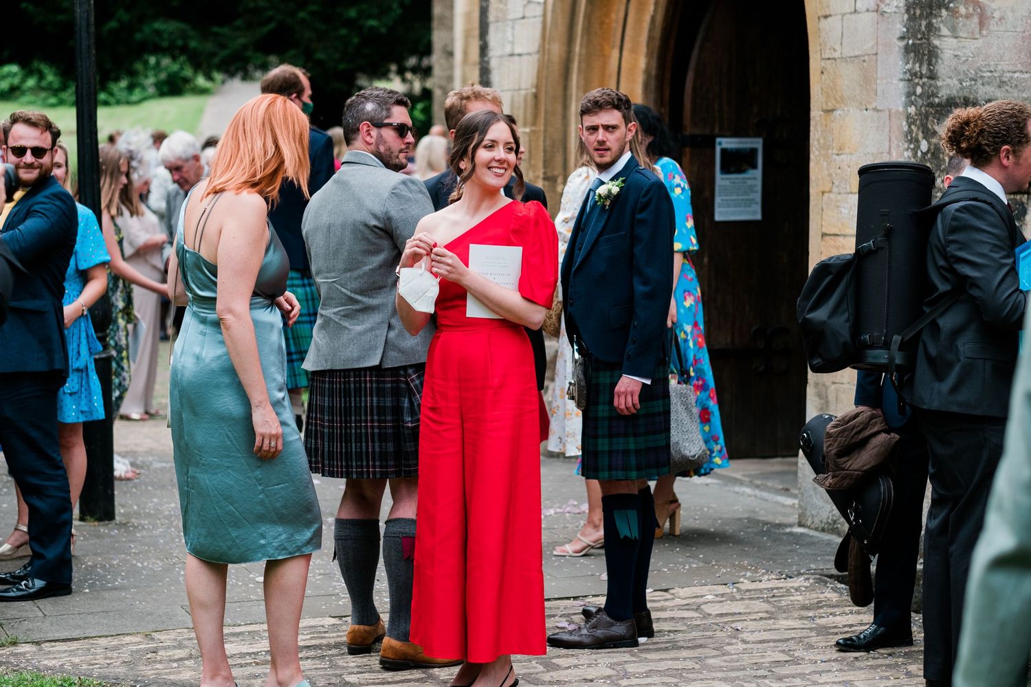 Guests in colorful attire socialize during outdoor wedding reception.