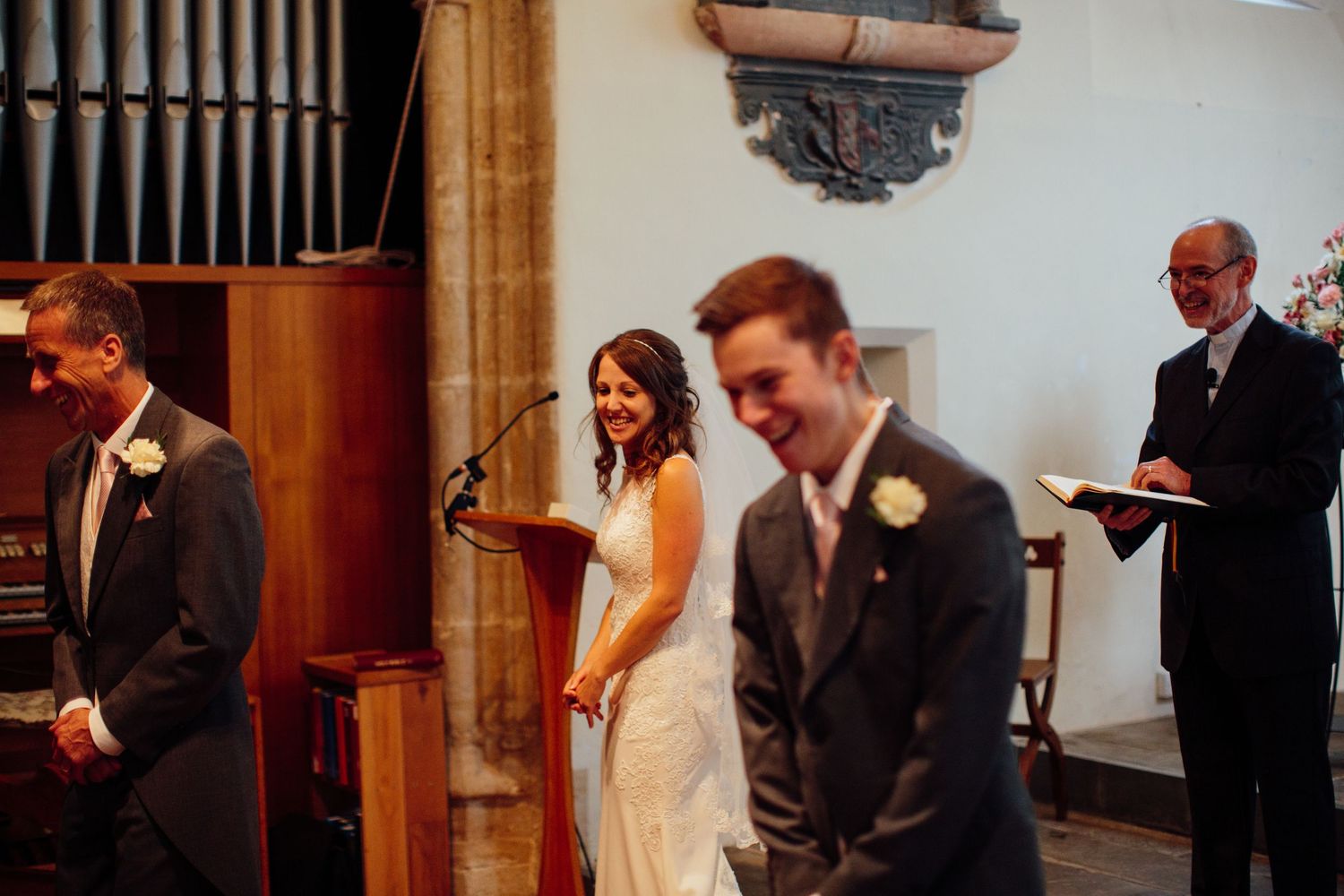 Wedding ceremony in a church with people standing at the altar near organ pipes.