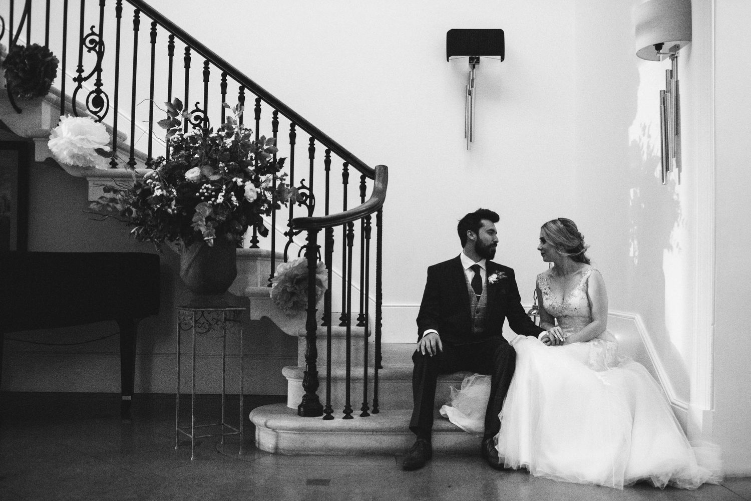 Black and white wedding photo with elegant staircase and iron railings.
