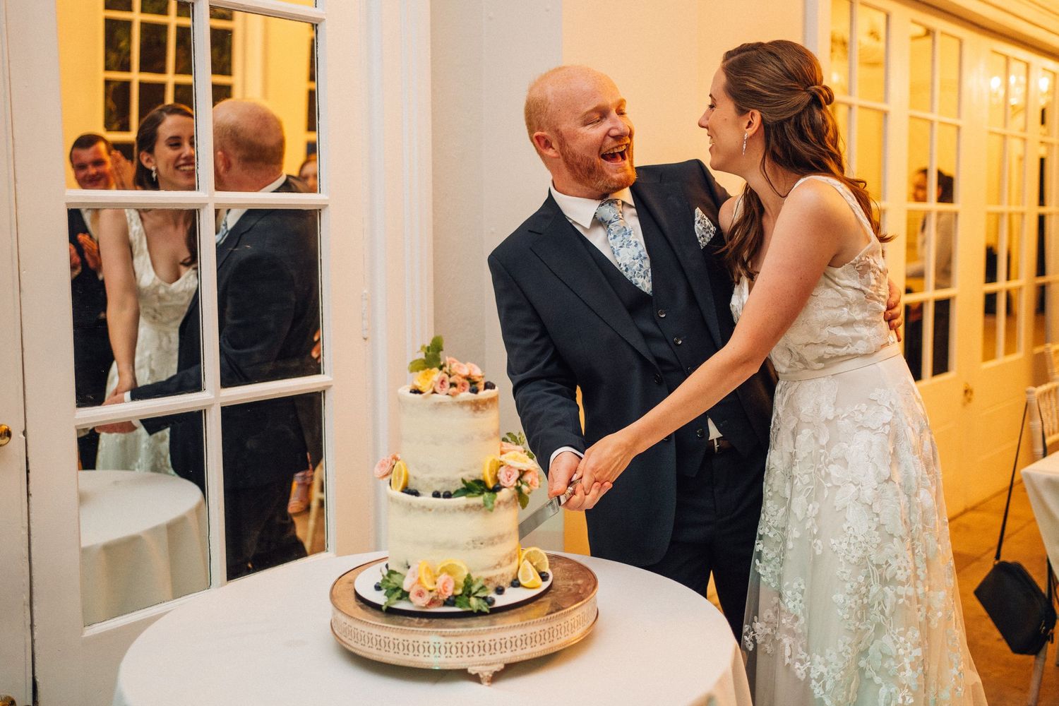 Wedding reception celebration with guests seated at decorated tables in a warmly lit venue.