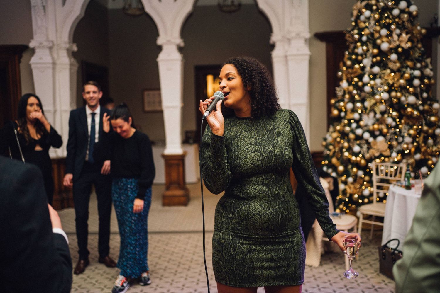 Guests enjoying themselves at an indoor wedding reception with festive holiday decorations.