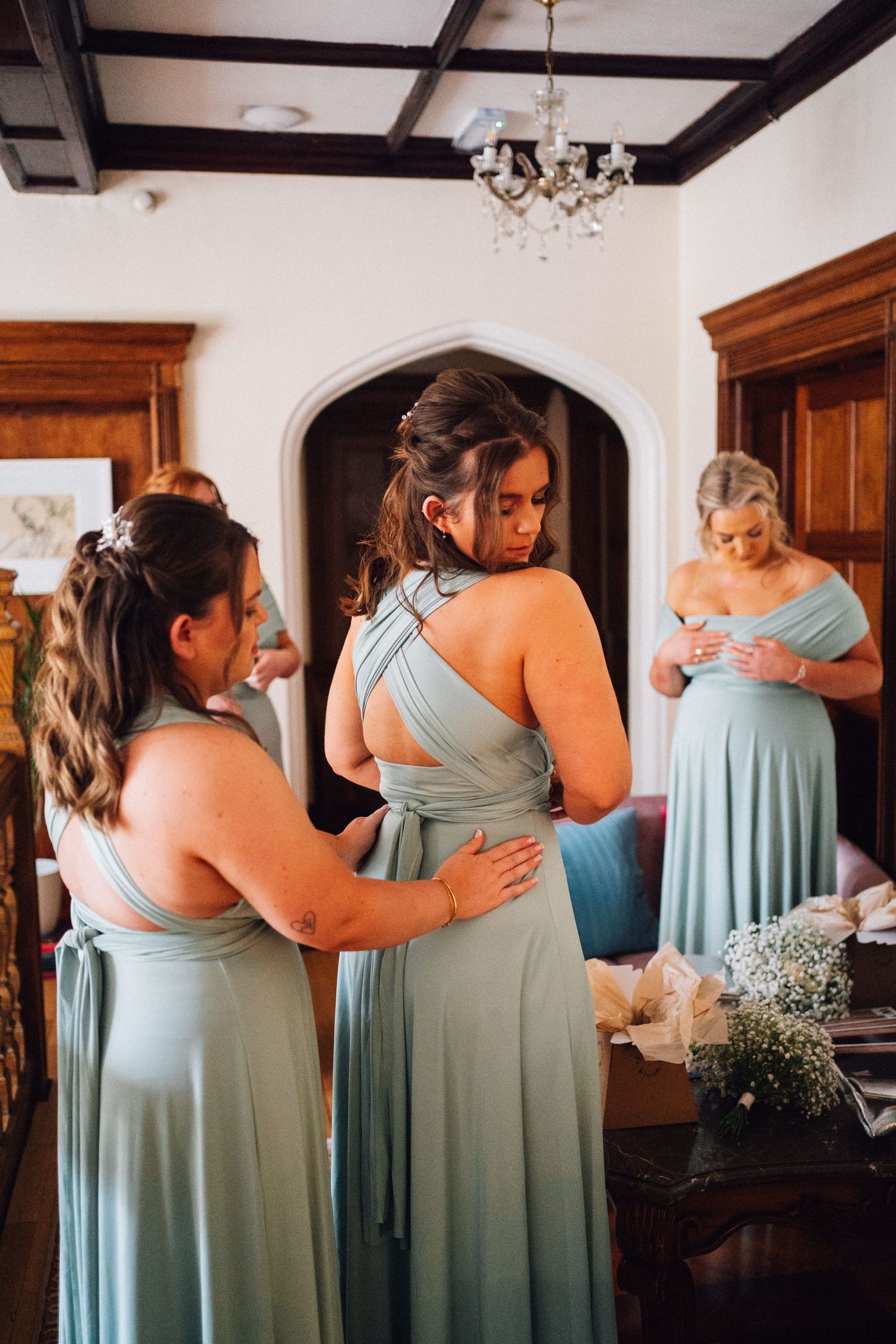 Bridesmaids in matching mint green dresses embrace in an emotional moment before the ceremony.