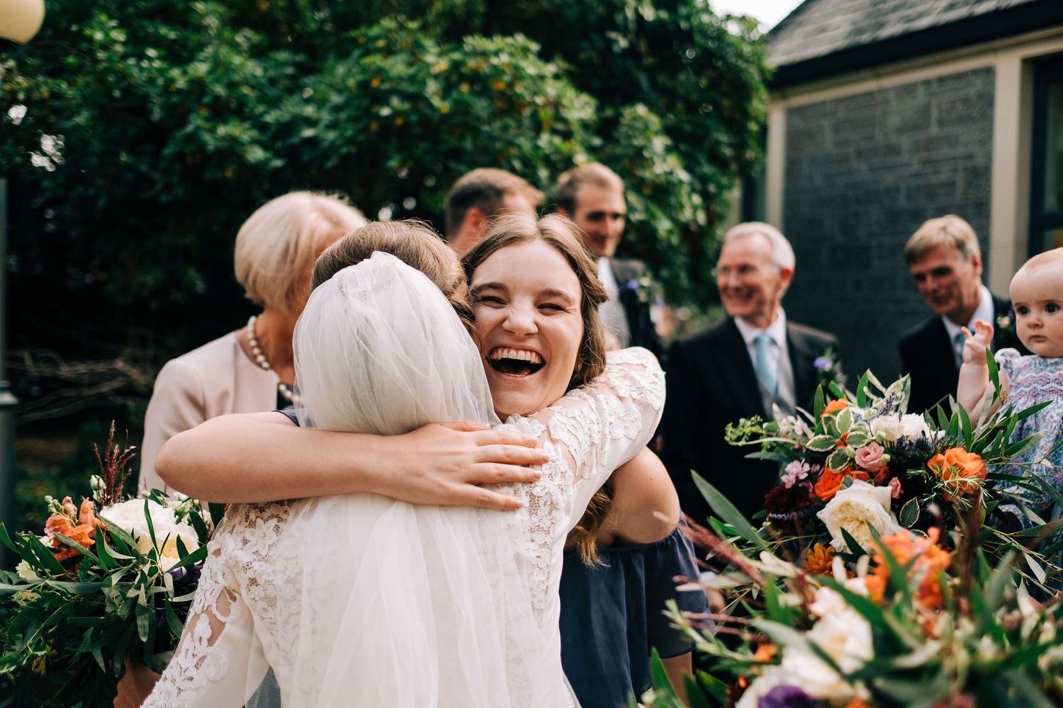 Wedding guests celebrate outdoors in lush garden setting.