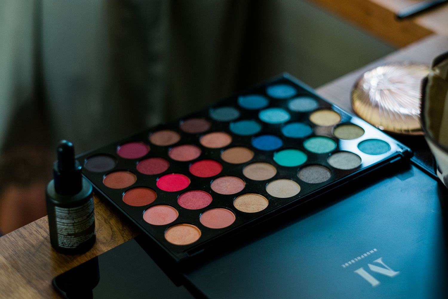 Colorful eyeshadow palette with vibrant blue and pink shades displayed on a dark surface.