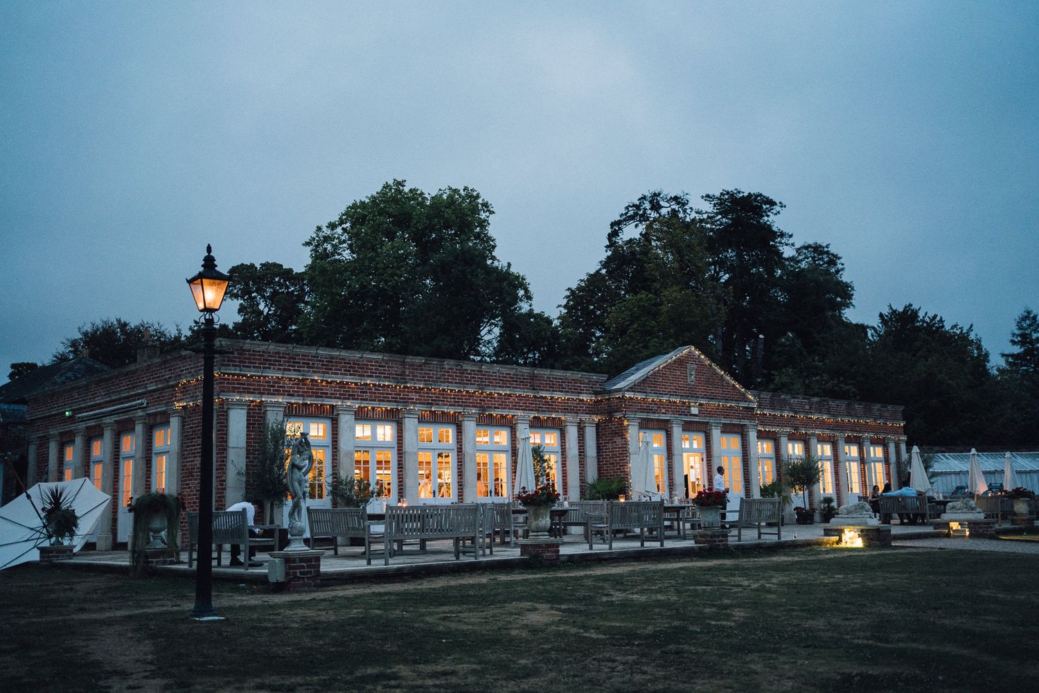 Panoramic exterior view of a brick building venue at dusk with illuminated windows.