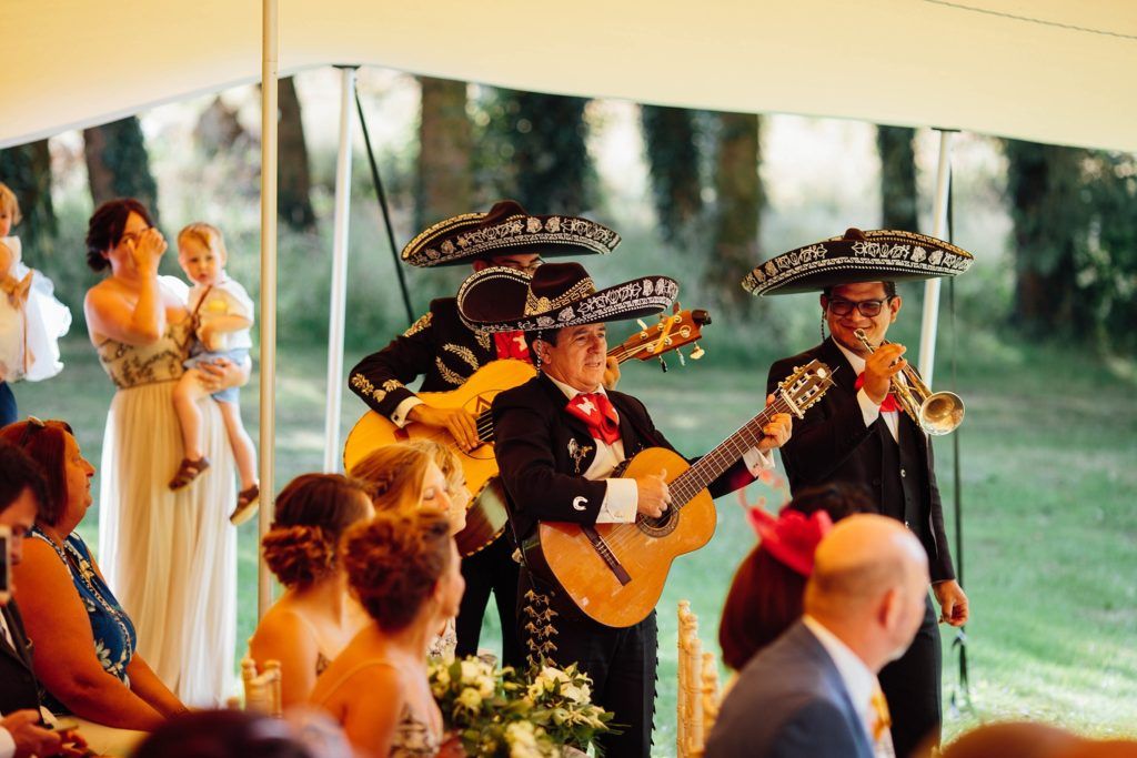 Wedding guests celebrate with live mariachi music during an outdoor reception.