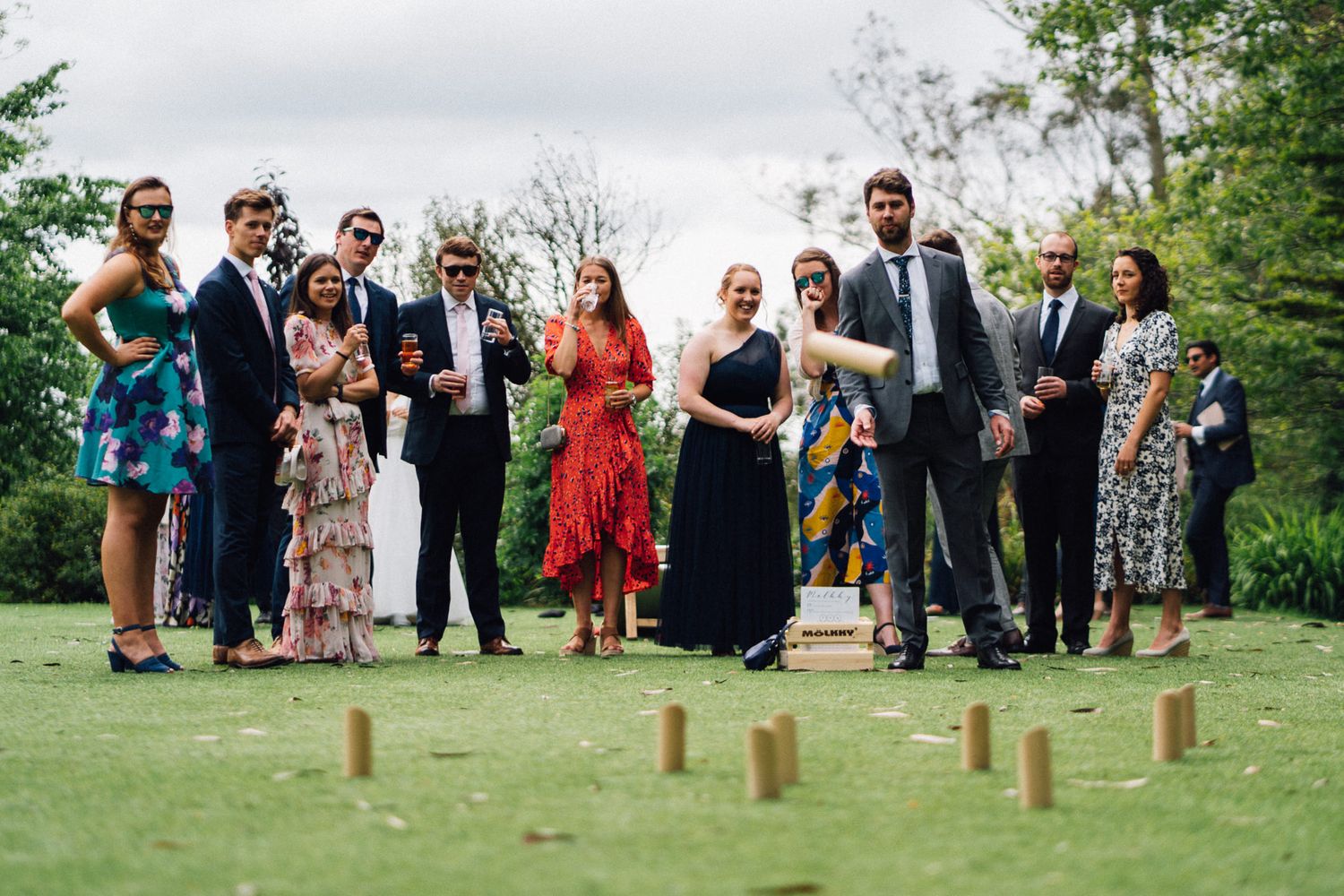 Large group of wedding guests playing lawn games at an outdoor summer celebration.