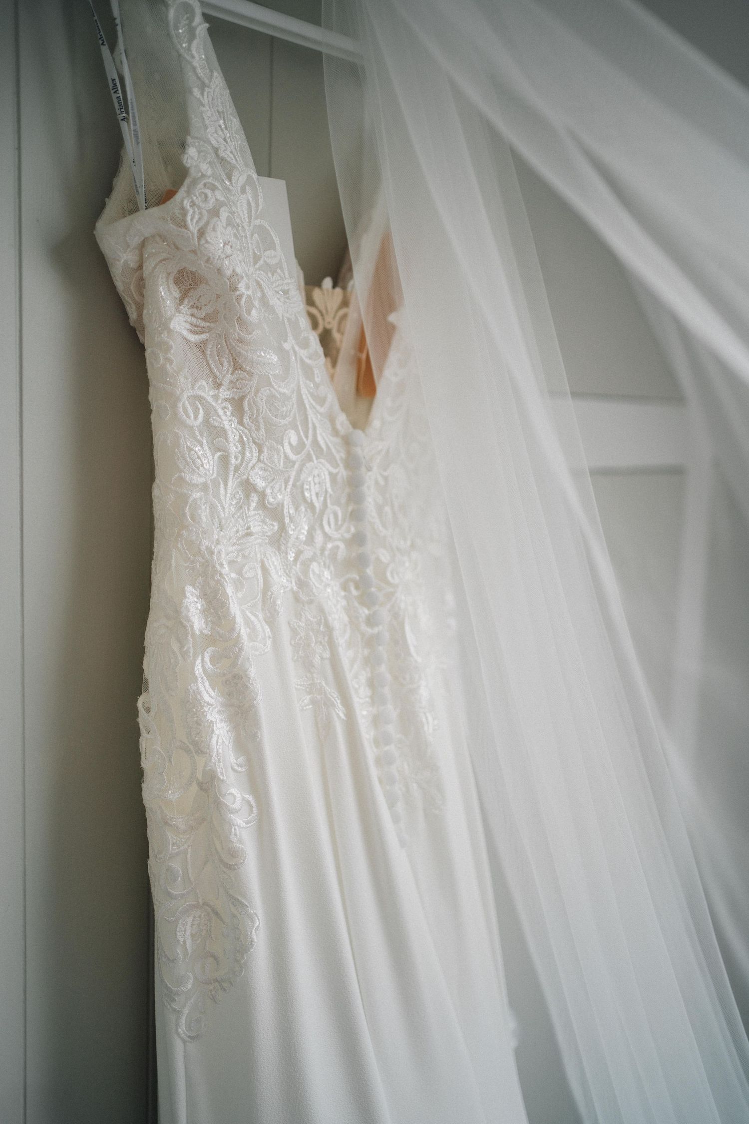 Close-up detail of delicate lace and tulle on a white wedding dress.