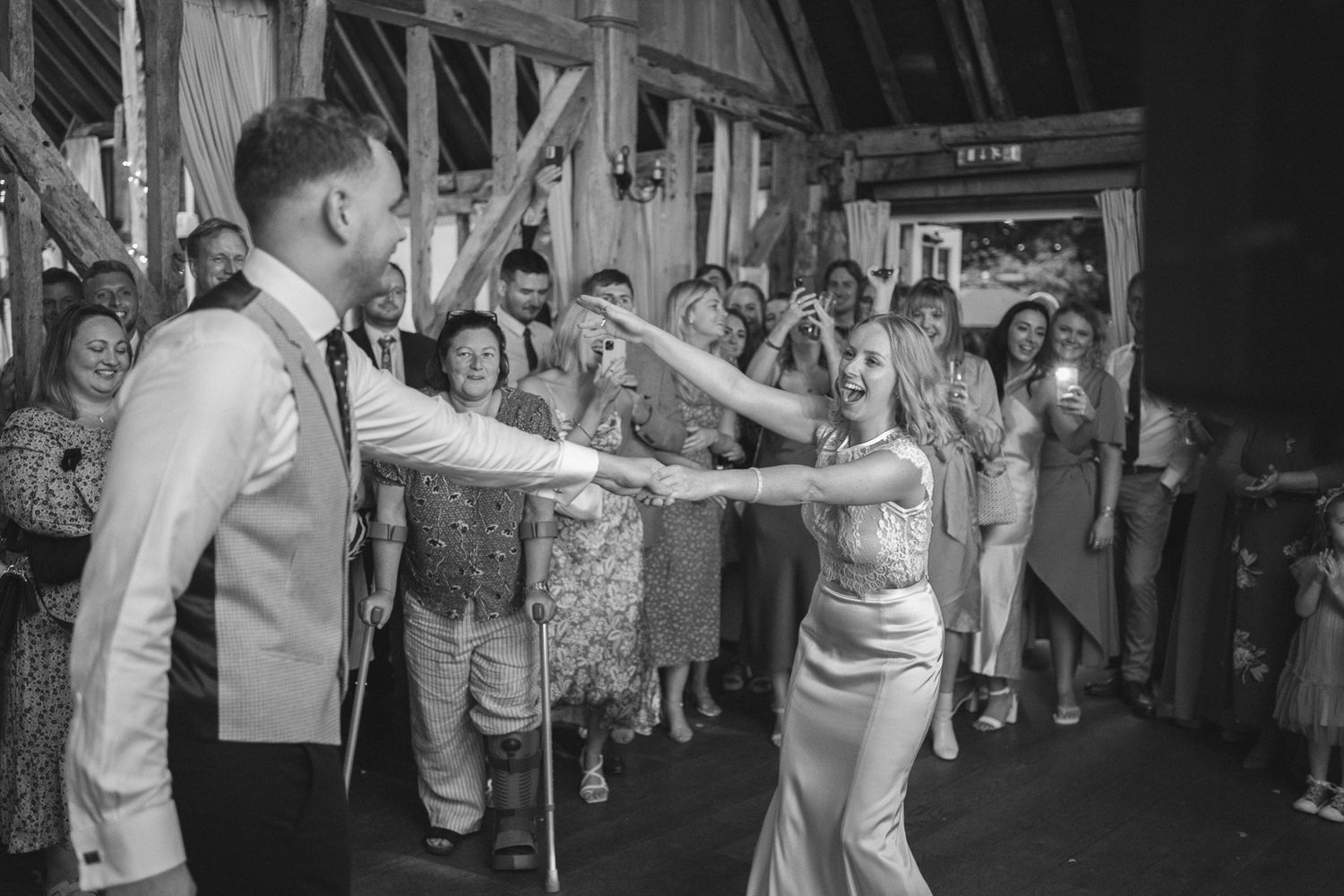 Wedding party exits through a tunnel of guests during an evening celebration with dramatic lighting.