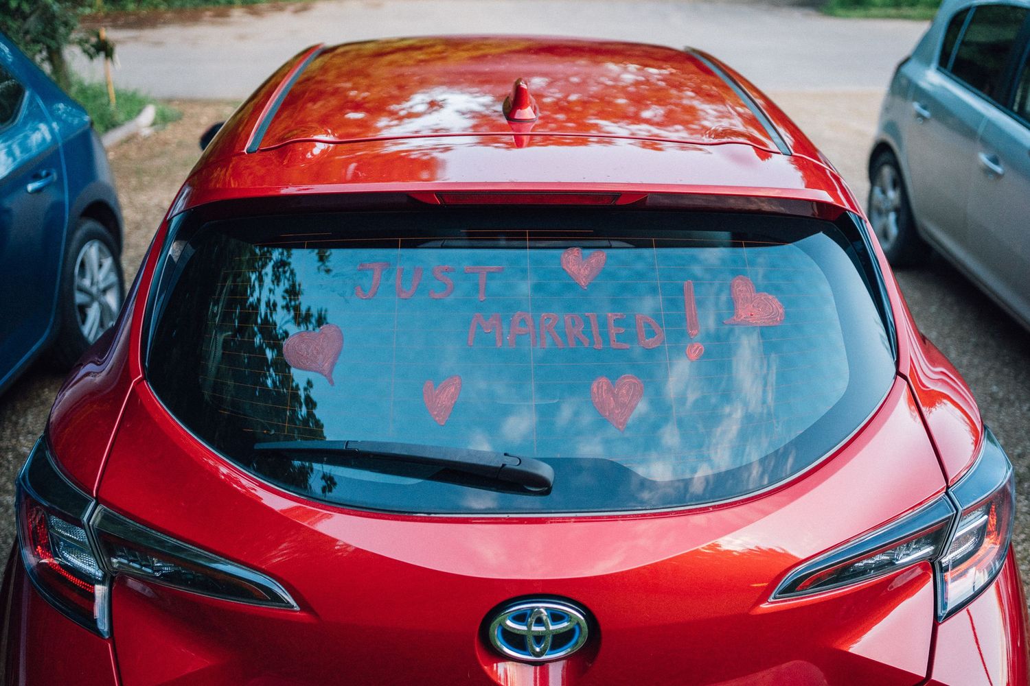 Red Toyota car decorated for a wedding celebration.