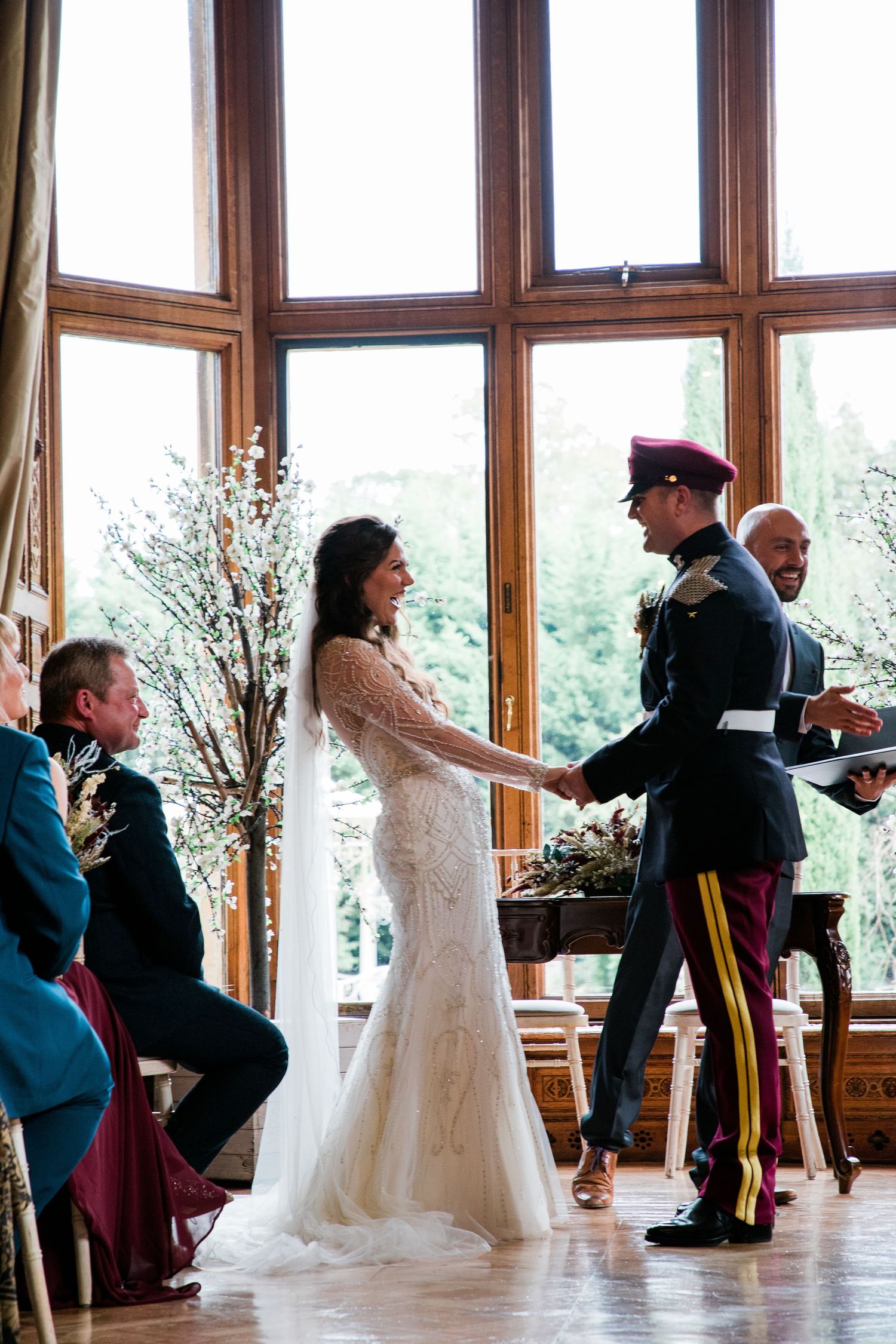 Wedding celebration in a sunlit room with wooden windows and floral decorations.