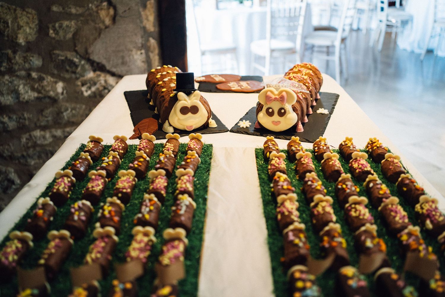 Rows of chocolate covered strawberries decorated with orange and green icing arranged on white serving platters.