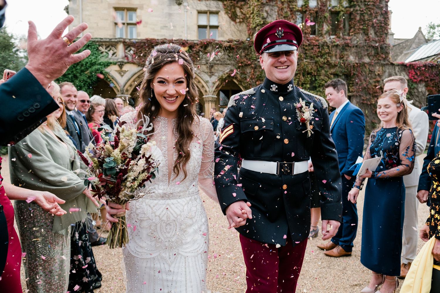 Joyful wedding celebration with confetti being thrown outside a historic stone venue.