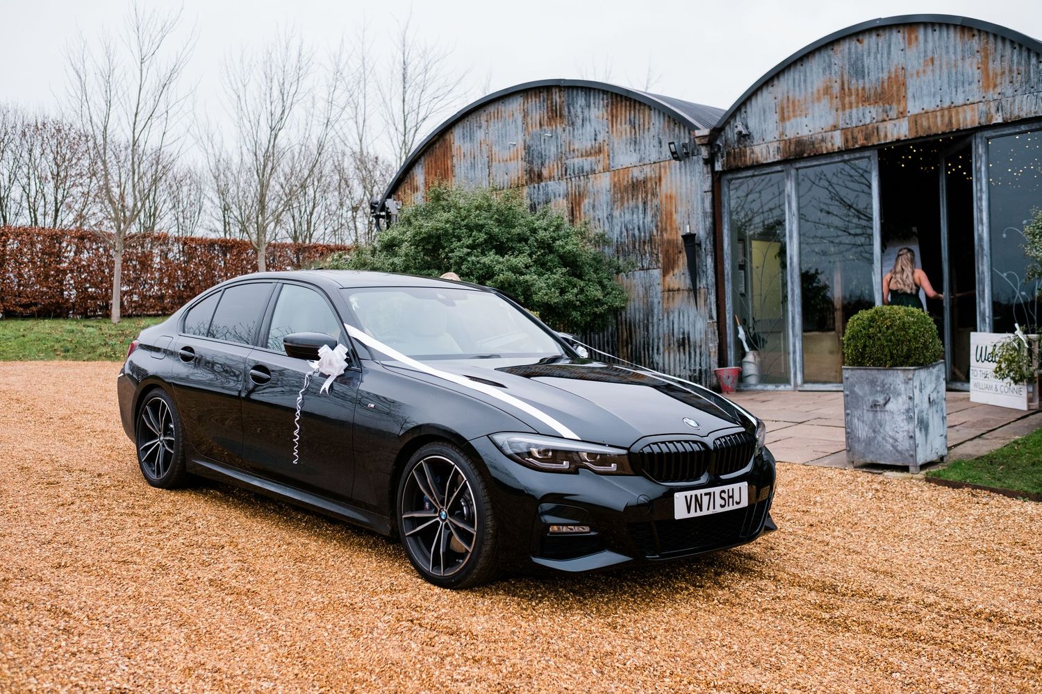 Luxury BMW vehicles parked outside a rustic stone barn venue.