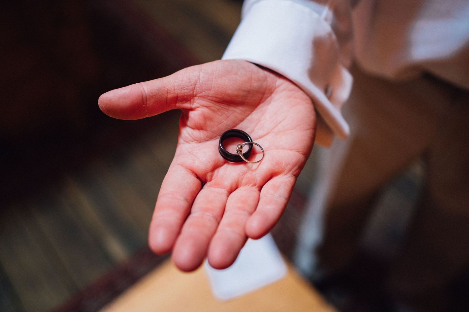 Close-up of wedding ring held in palm of white dress shirt sleeve.