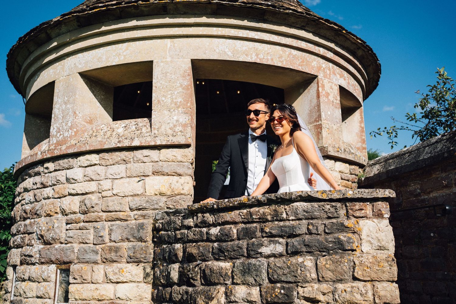 Wedding photography session at a historic stone turret under blue skies.