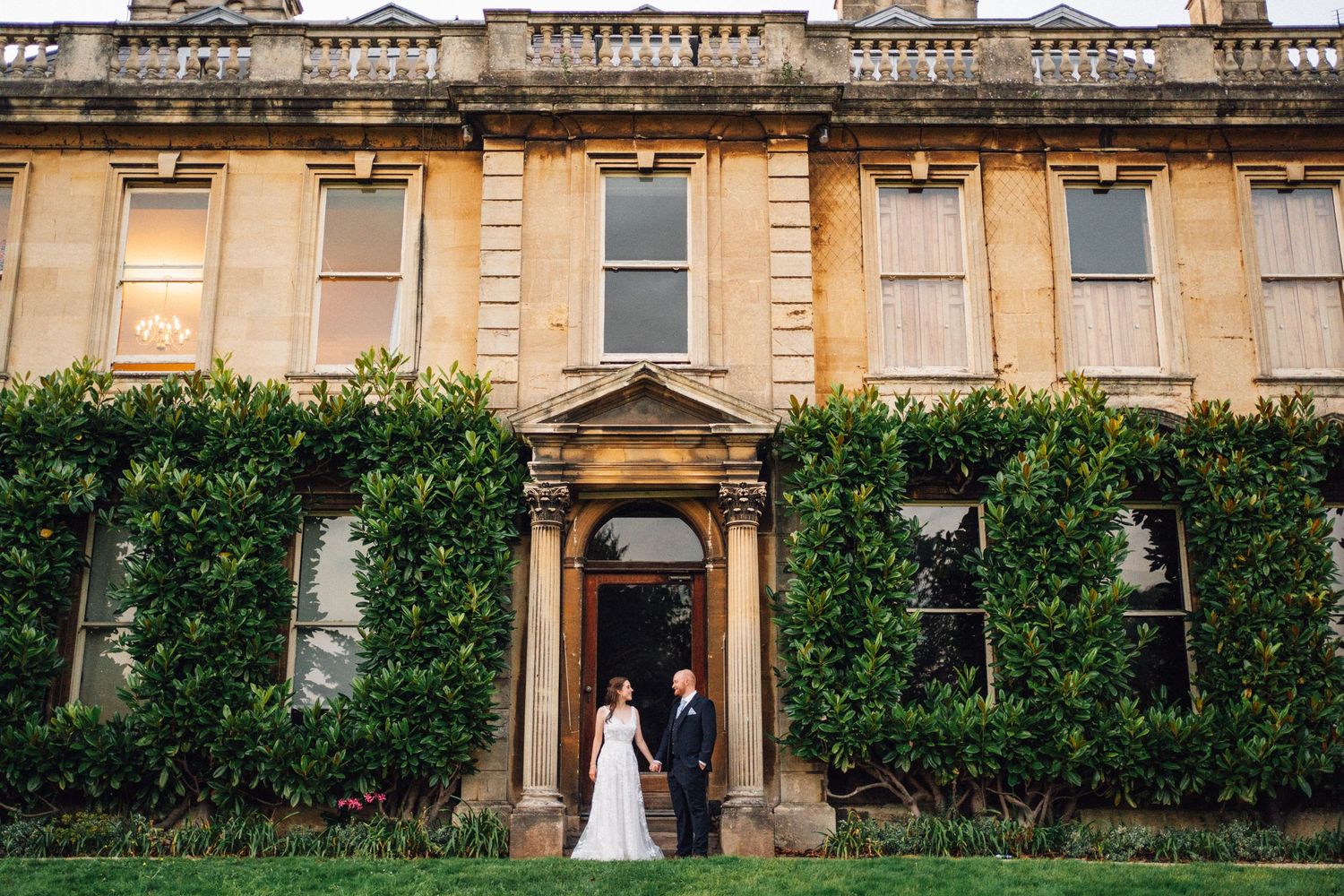 Classic stone architecture with ornate balustrades and manicured hedges along the facade.