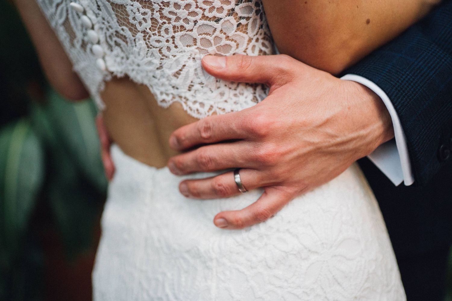 Close-up details of white lace wedding dress with delicate beading.