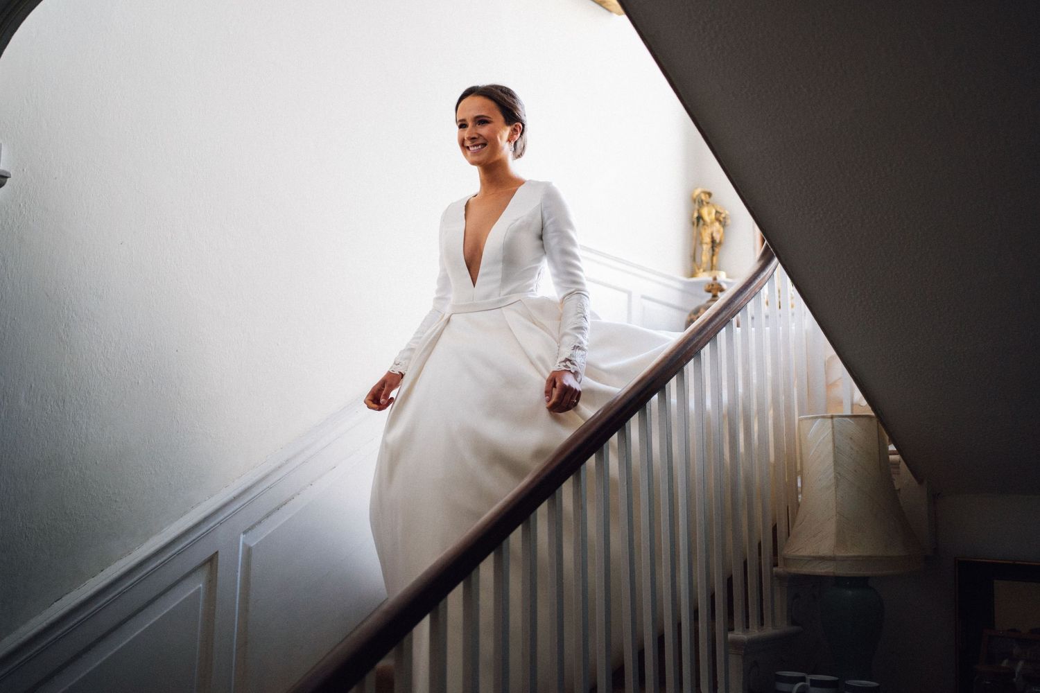 Elegant wedding dress photographed on a white staircase in natural light.