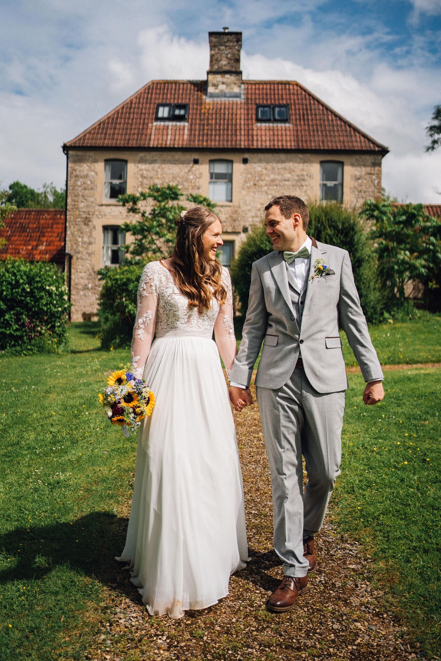 Couple walking together on a path outside a traditional stone building.