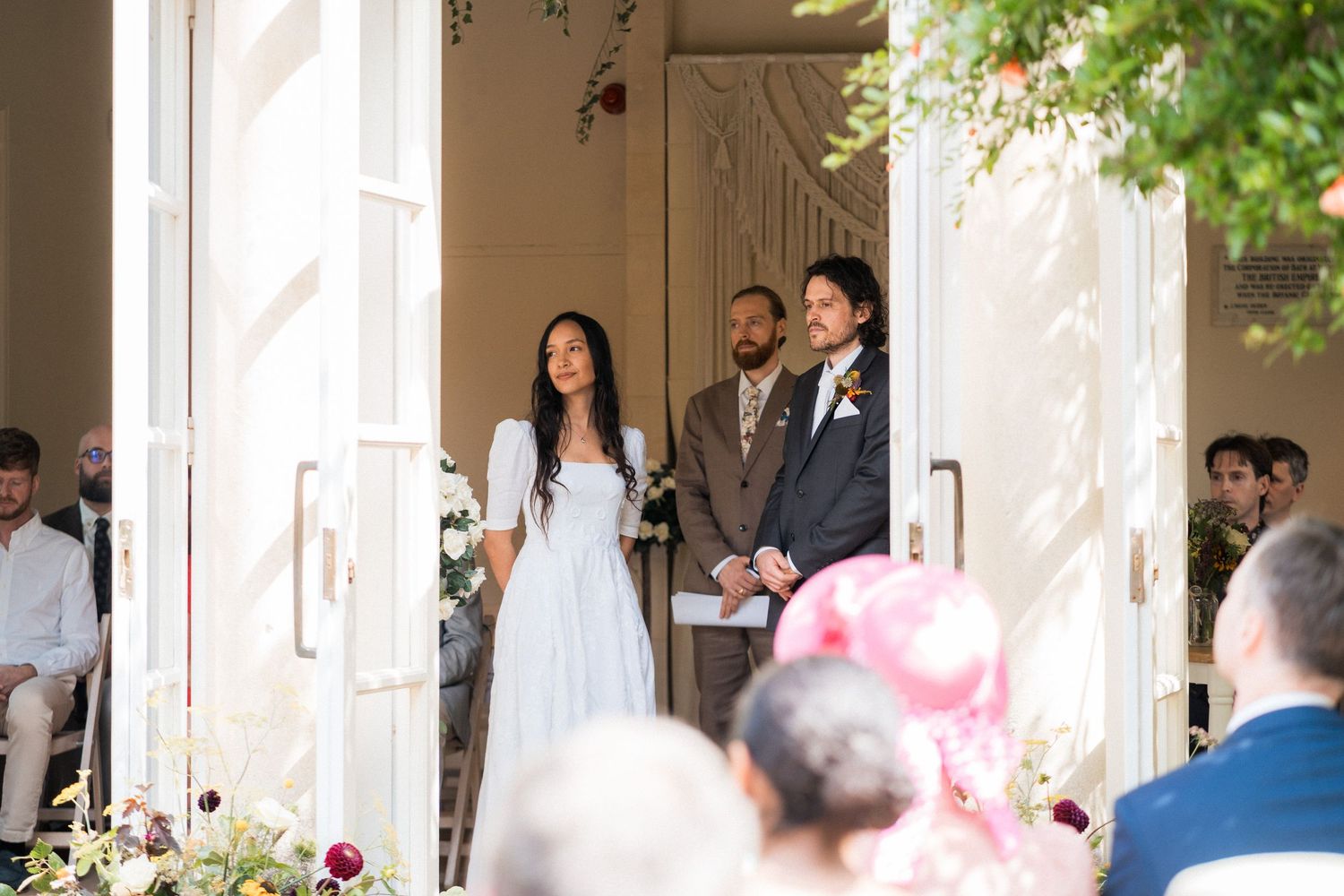 Bride and groom standing at wedding ceremony entrance, bride in light blue dress, groom in gray suit.