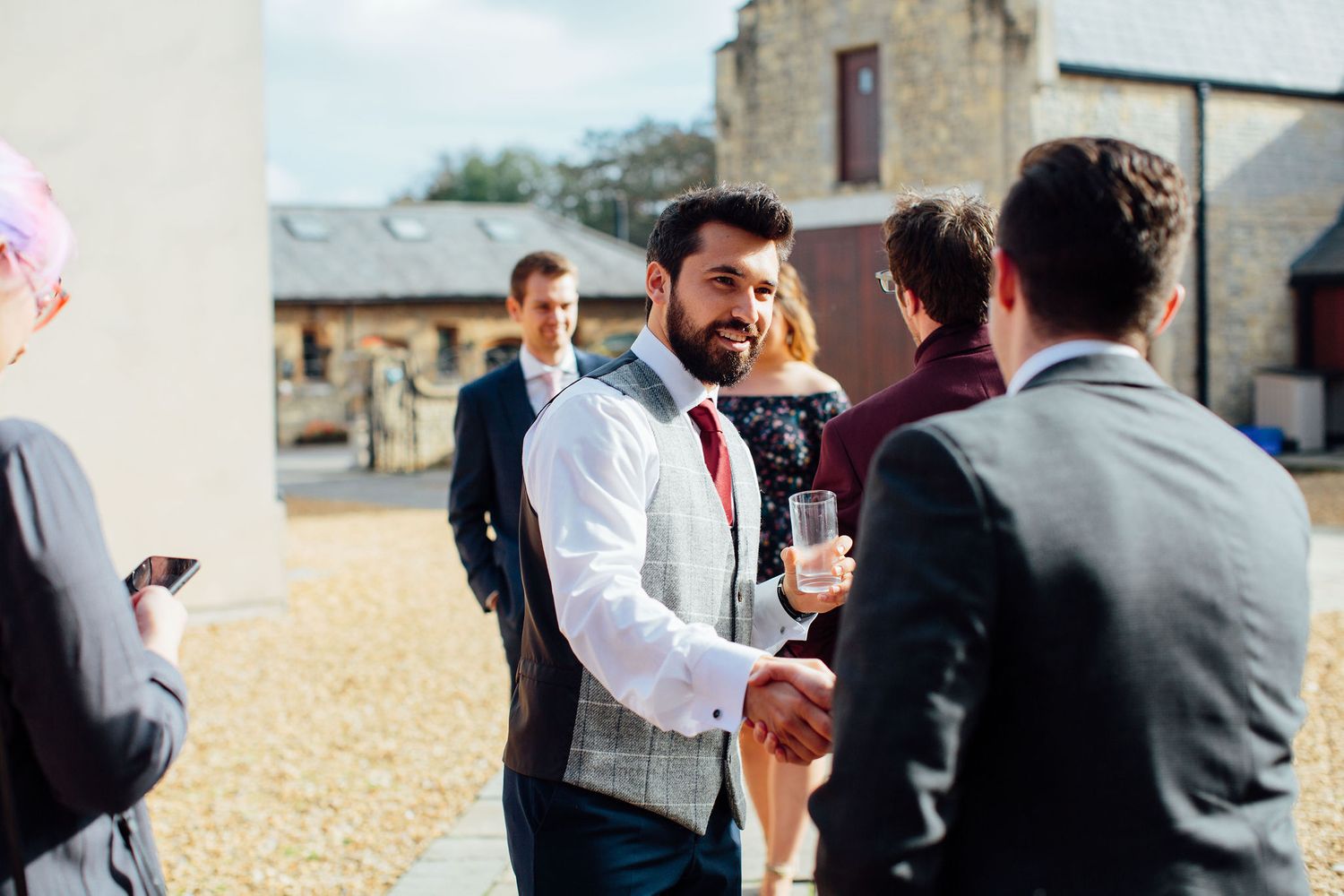 Guests socializing outdoors at an event near a stone building.