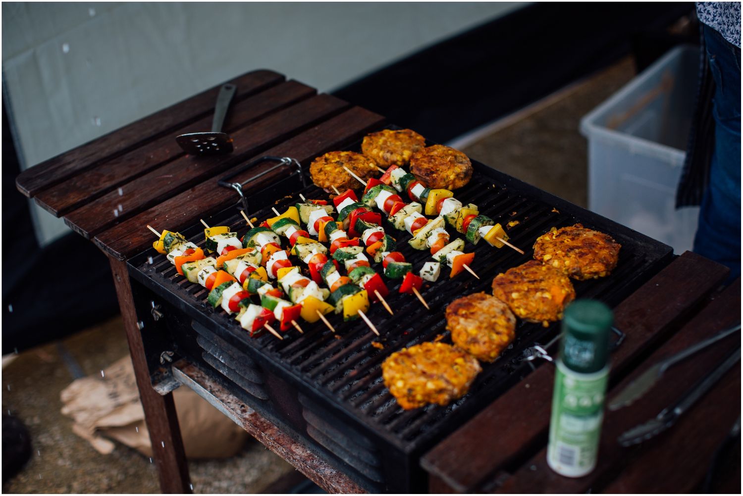 Grilled kebabs and meat cooking on a wooden outdoor barbecue.