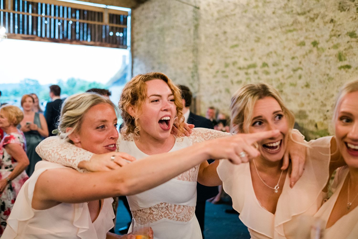 Wedding guests celebrating with energetic dance moves at an indoor reception.