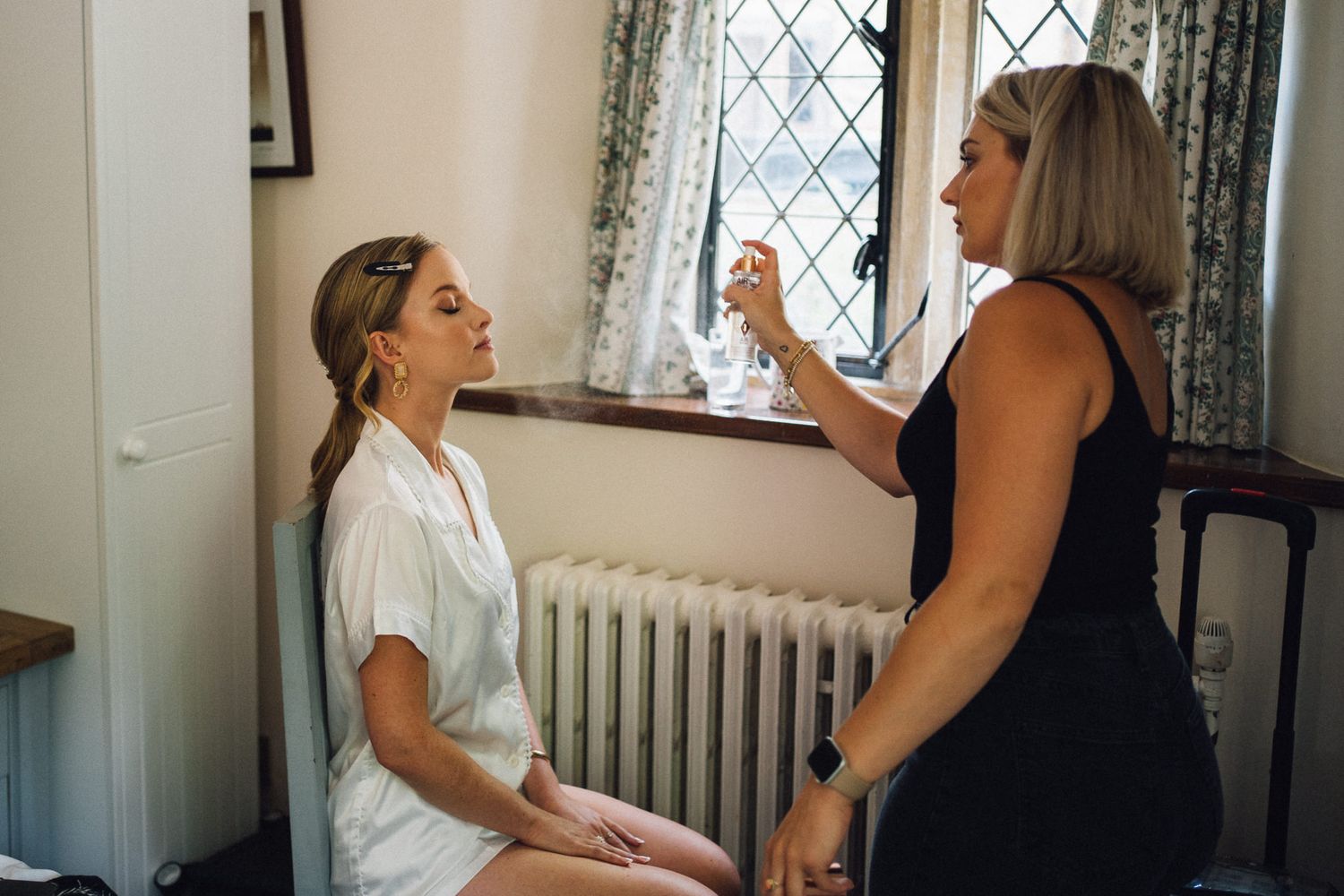 Wedding preparation scene in a rustic room with stone walls and diamond-paned windows.