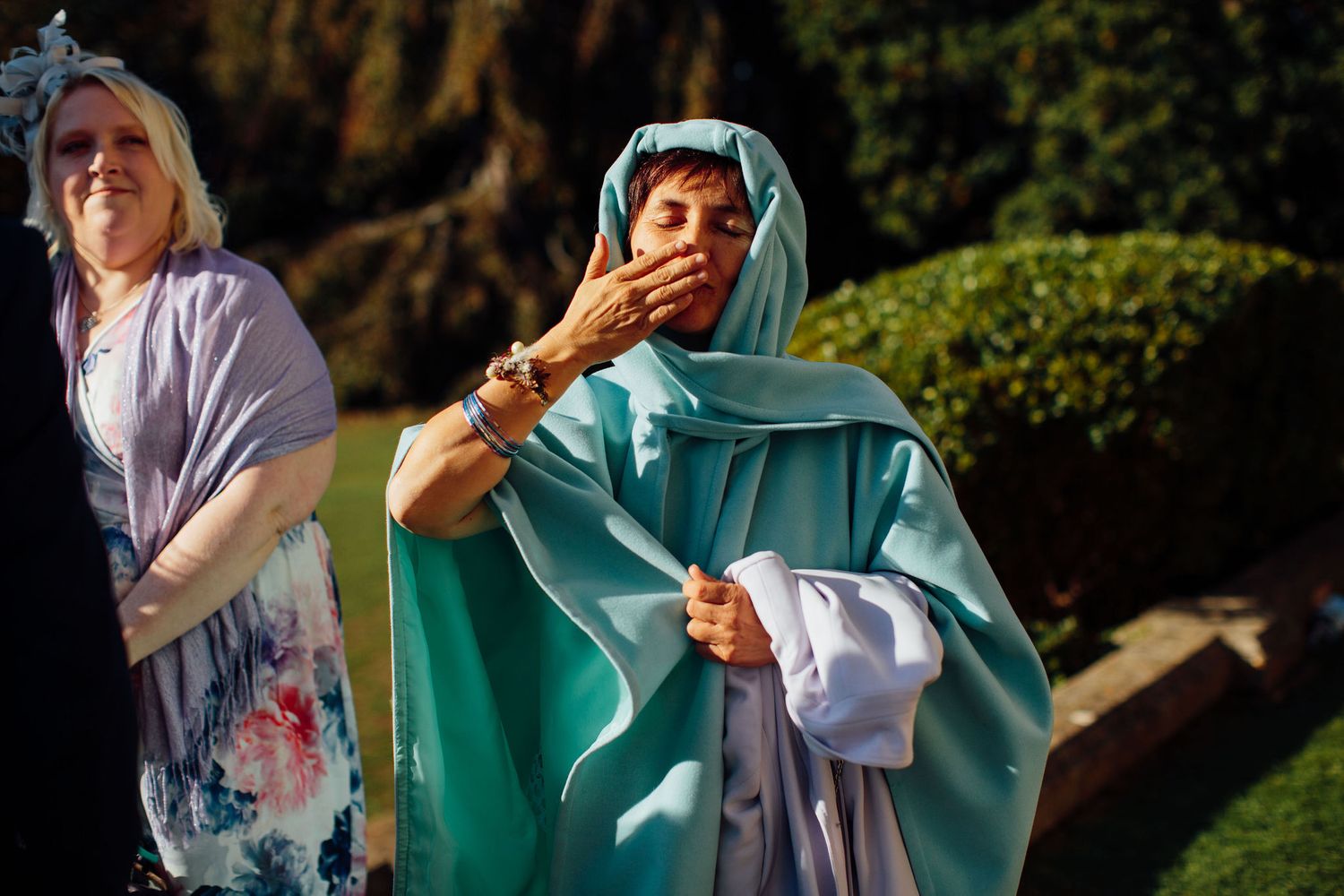 Wedding guests in formal attire applauding during an outdoor celebration.