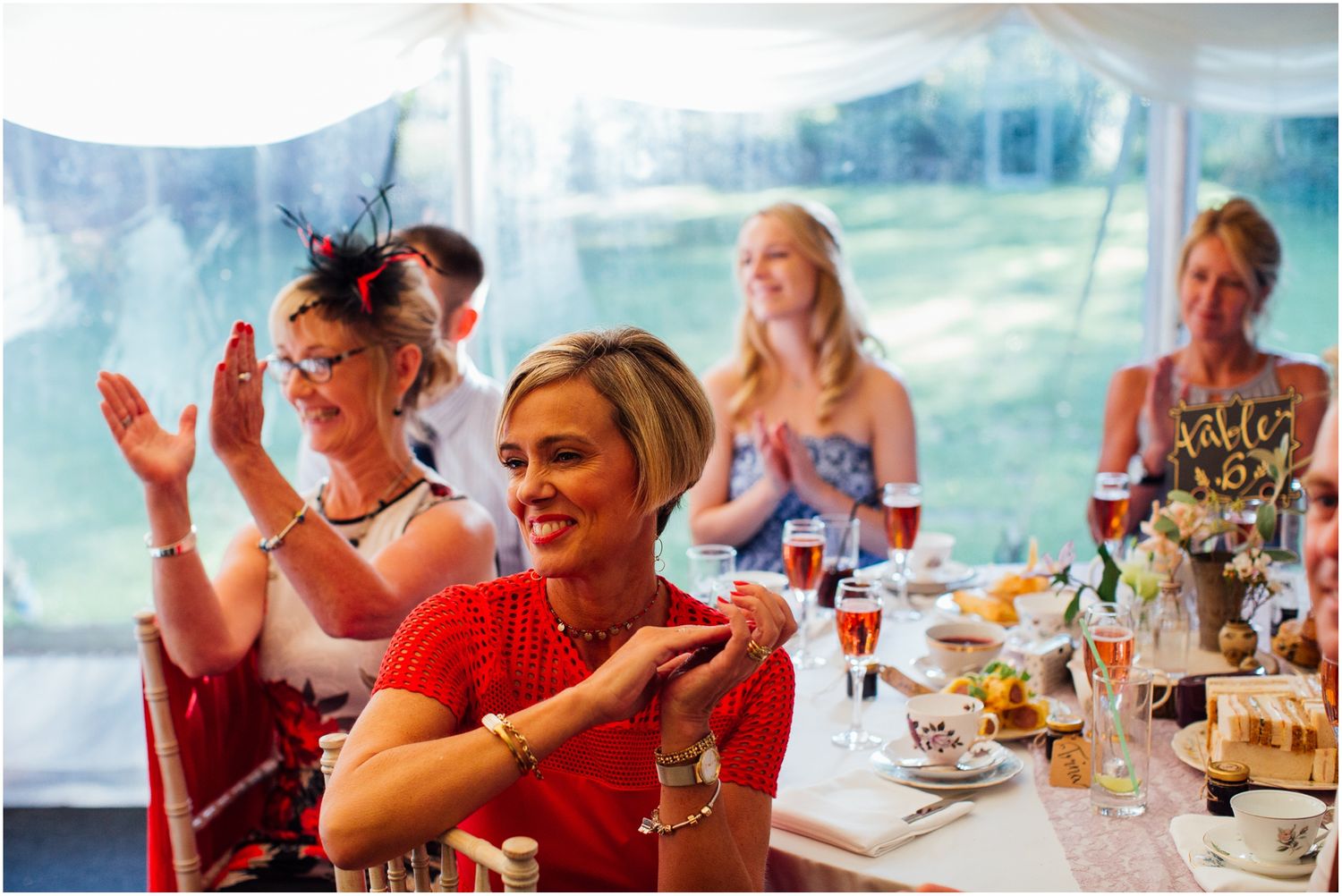 Guests enjoying a meal at a wedding reception under a white tent.