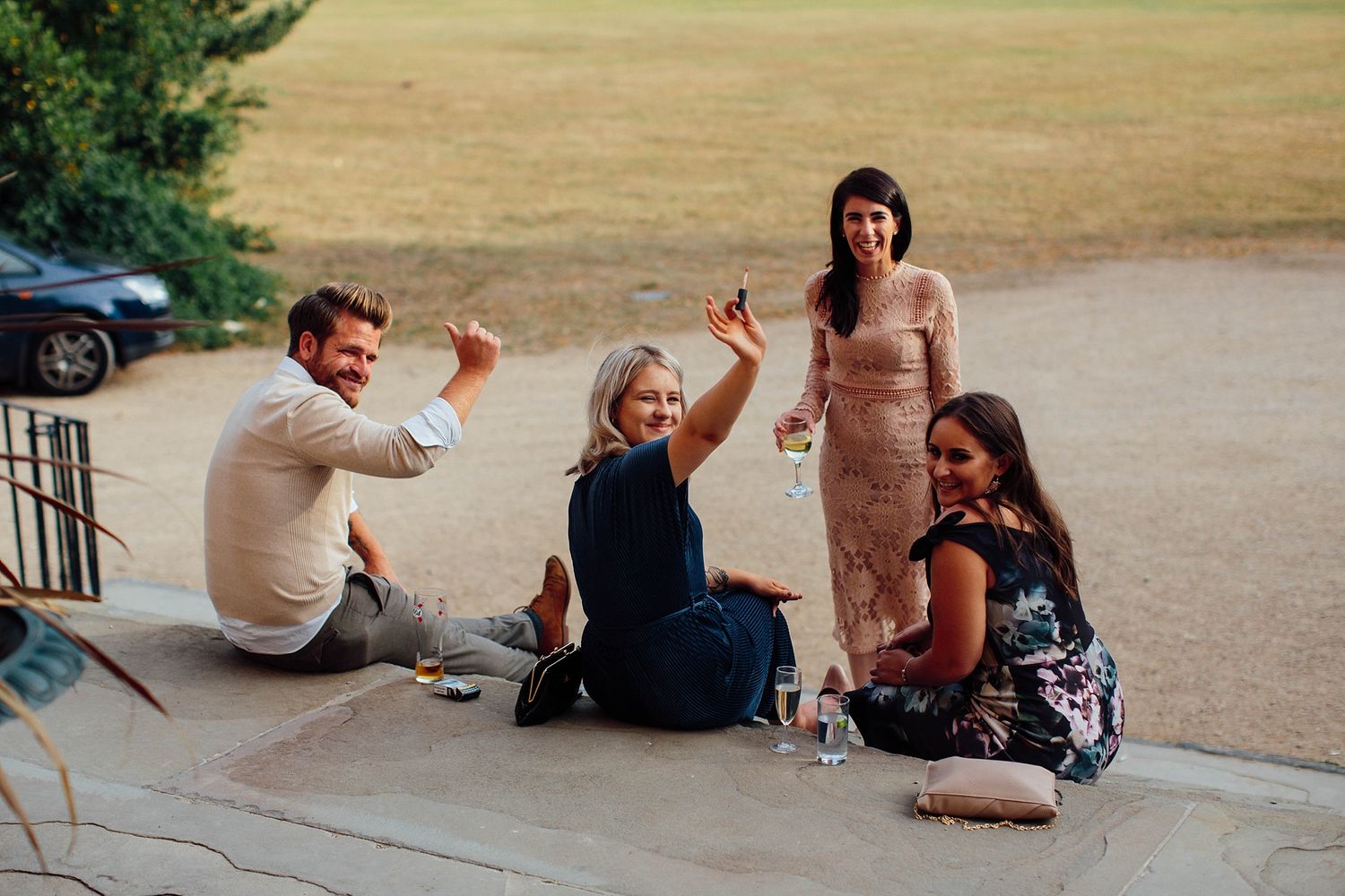 Wedding guests relax and socialize on outdoor steps during a casual moment at the reception.