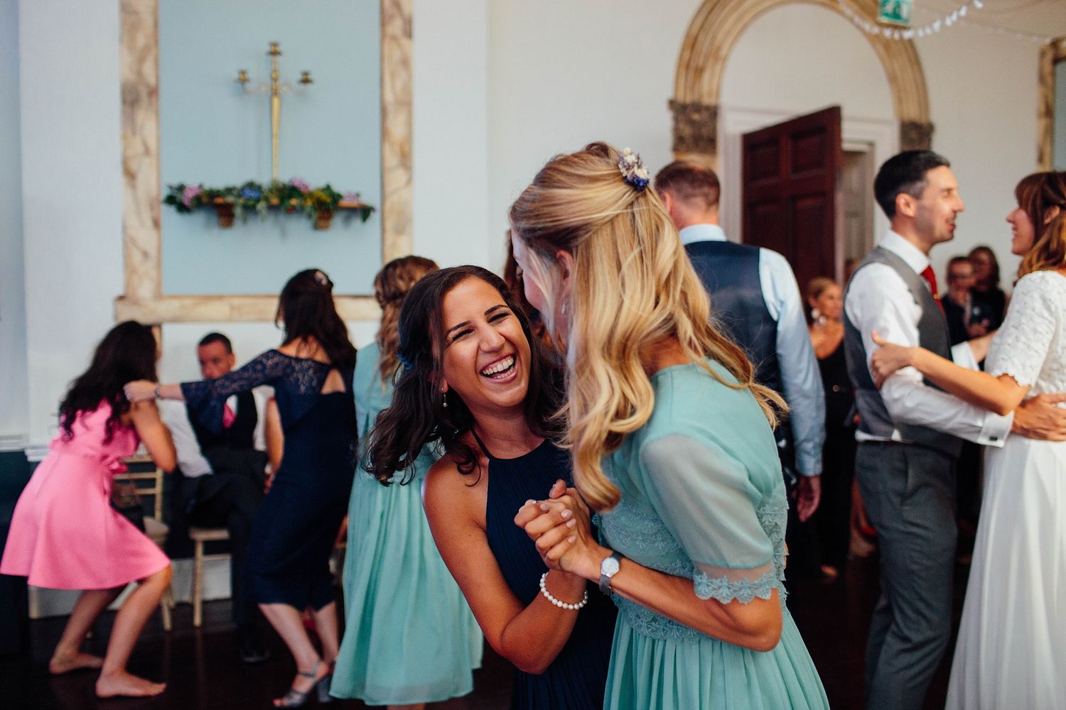 Guests enjoying themselves at an indoor wedding reception with teal and navy attire.