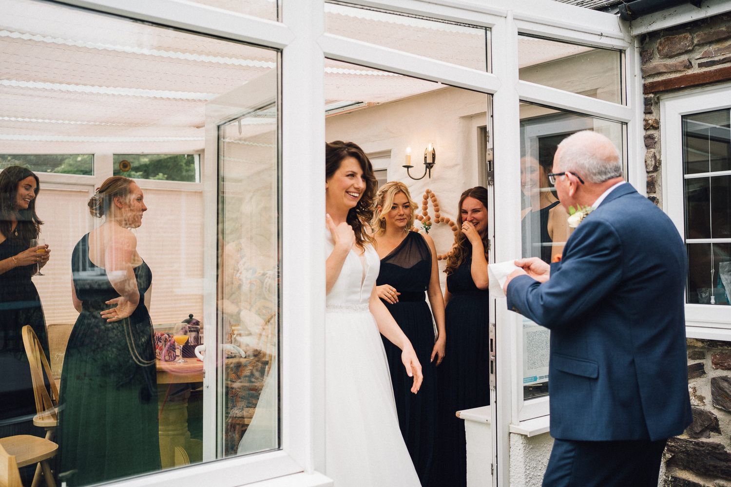 Wedding party members share emotional first look reactions in a series of candid moments outside a stone building.