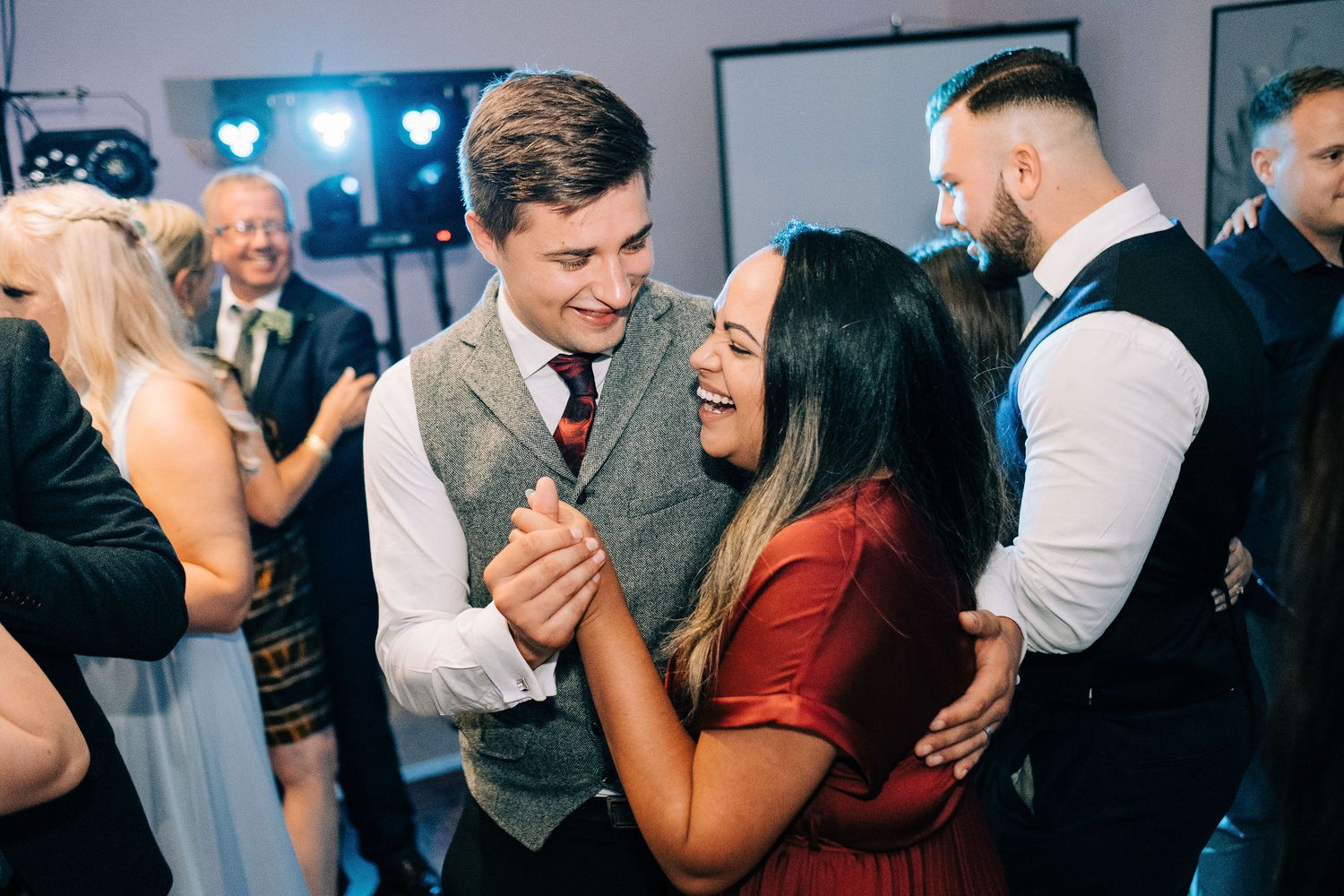 Wedding guests enjoying themselves on a lively dance floor with party lighting.