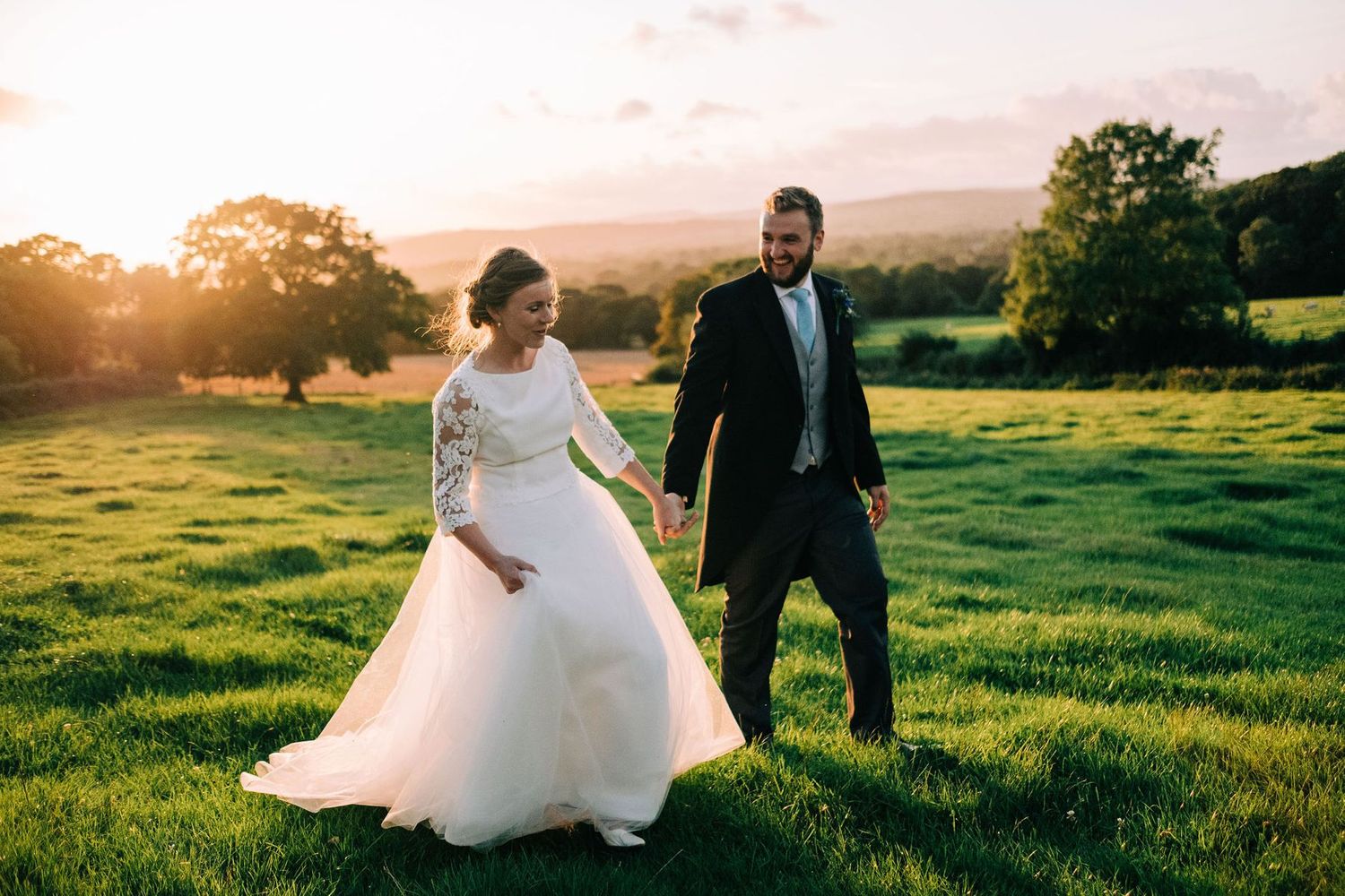 Newlyweds share romantic moments in a sunlit meadow during golden hour photography session.