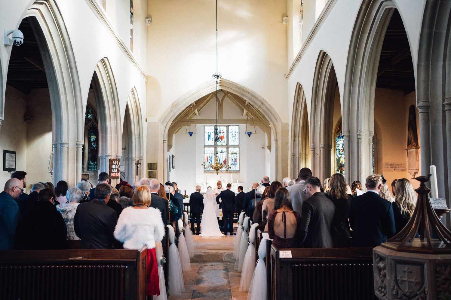 Wedding ceremony taking place in a traditional church with Gothic arches and wooden pews.
