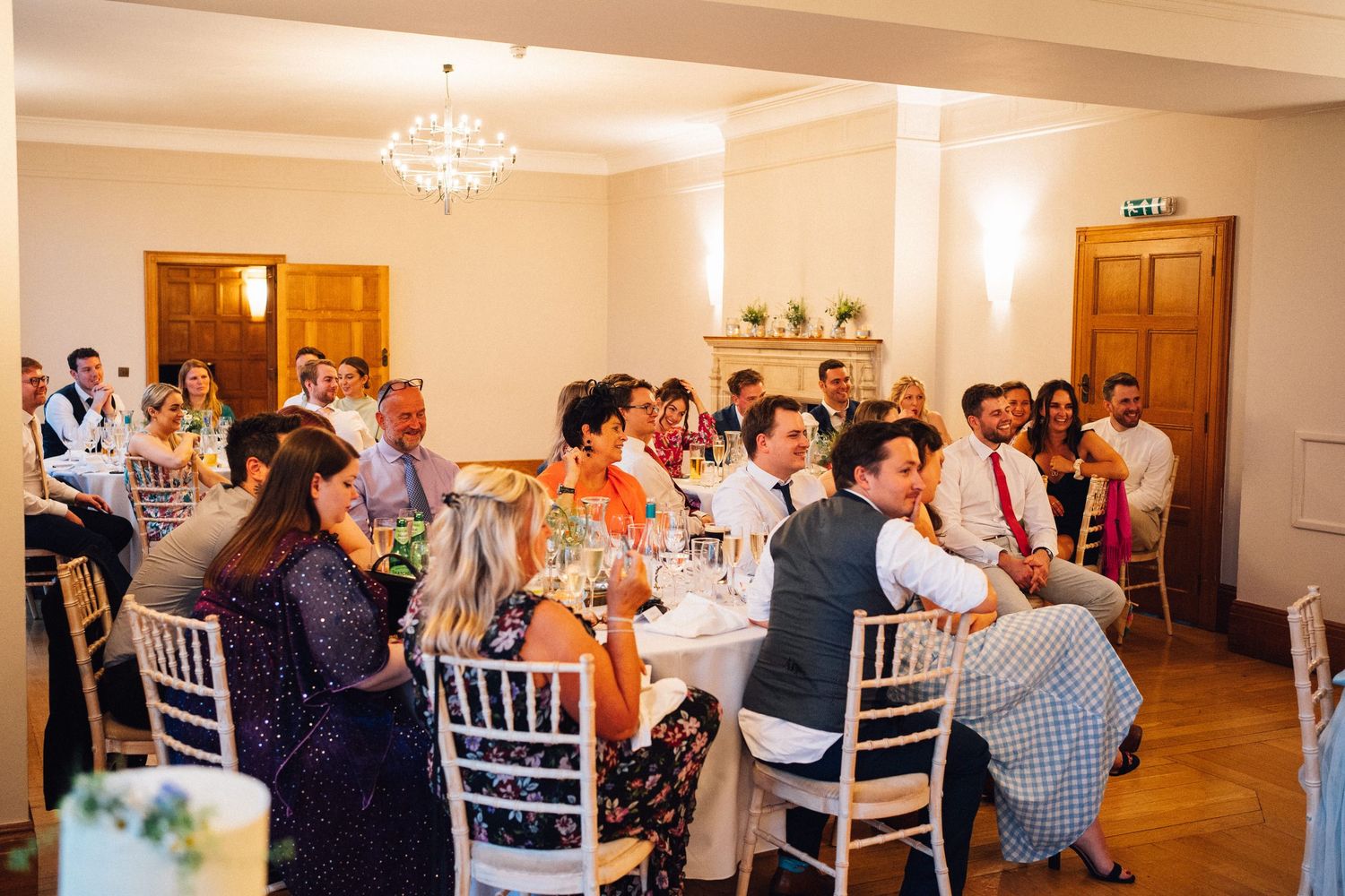 Wedding reception dining room with white chairs and tables set for guests.