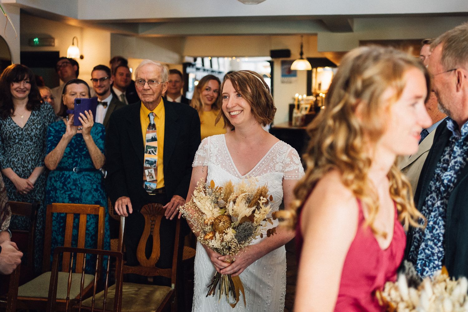 Wedding guests celebrate and laugh together during a reception at an indoor venue.